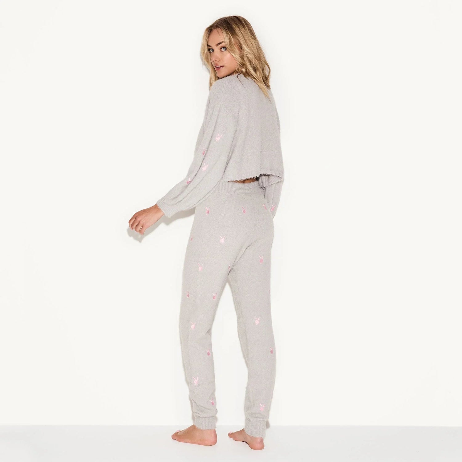 Woman wearing grey fluffy knit leggings with pink graphic print, paired with matching sweater