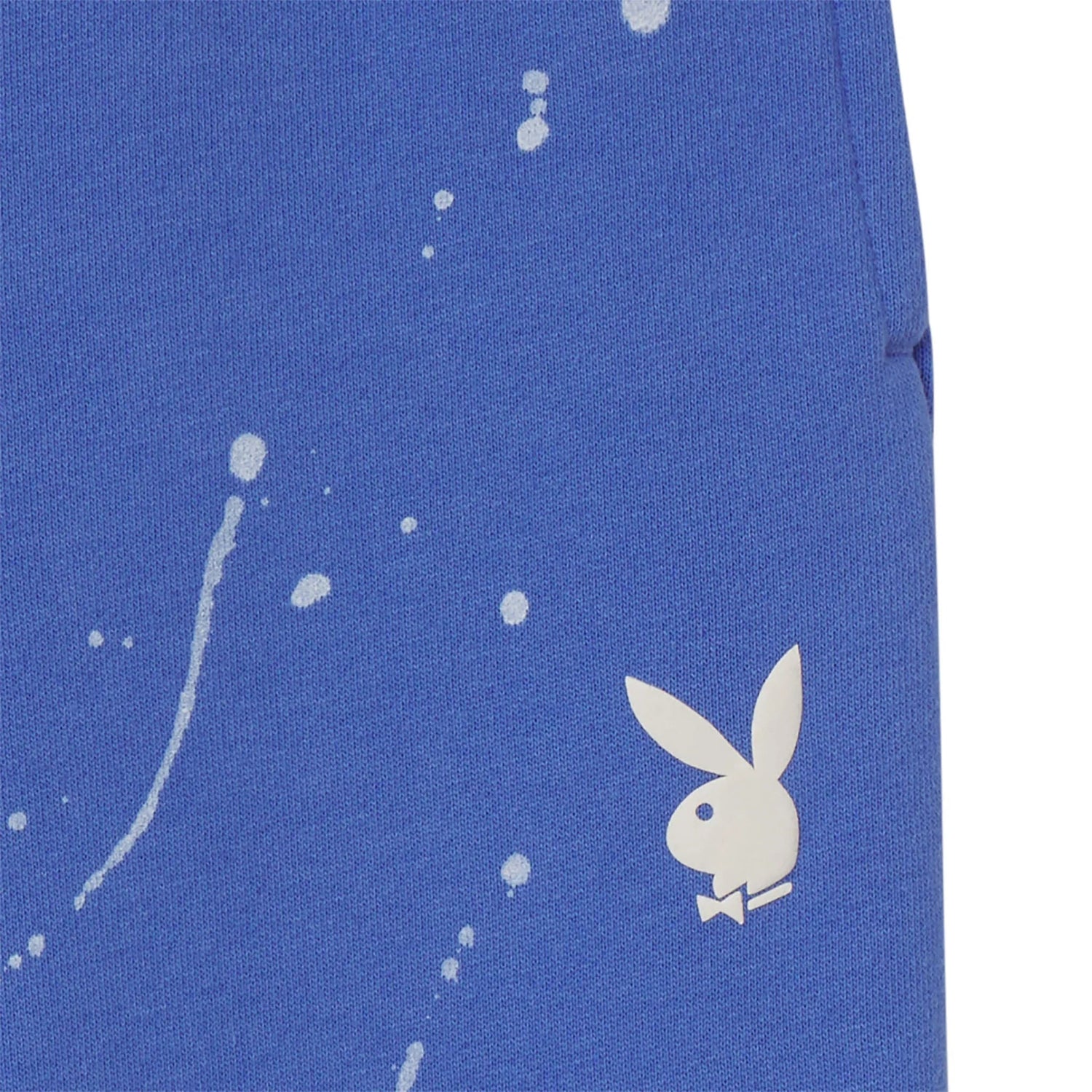 Close-up of blue women's sweatpants with white splatter print and bunny logo graphic