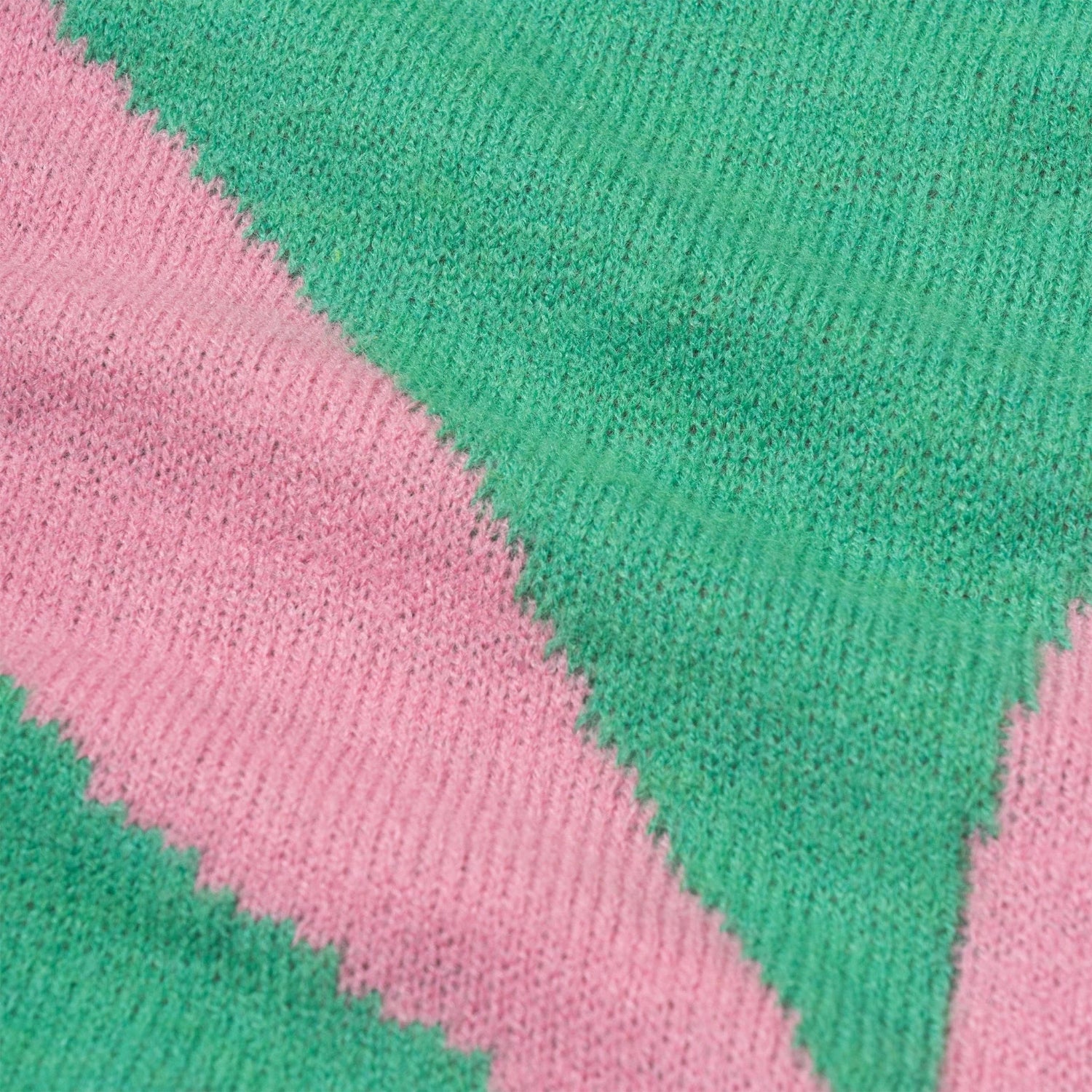 Close-up of knit scarf fabric with pink and green diagonal stripes, soft texture
