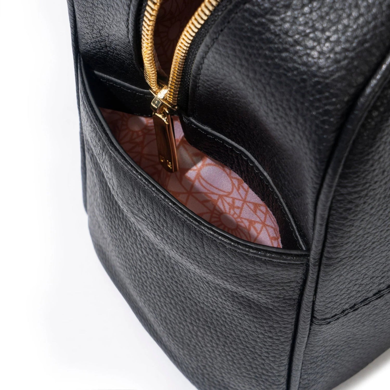 Close-up of black leather mini backpack with gold zipper and patterned pink fabric lining
