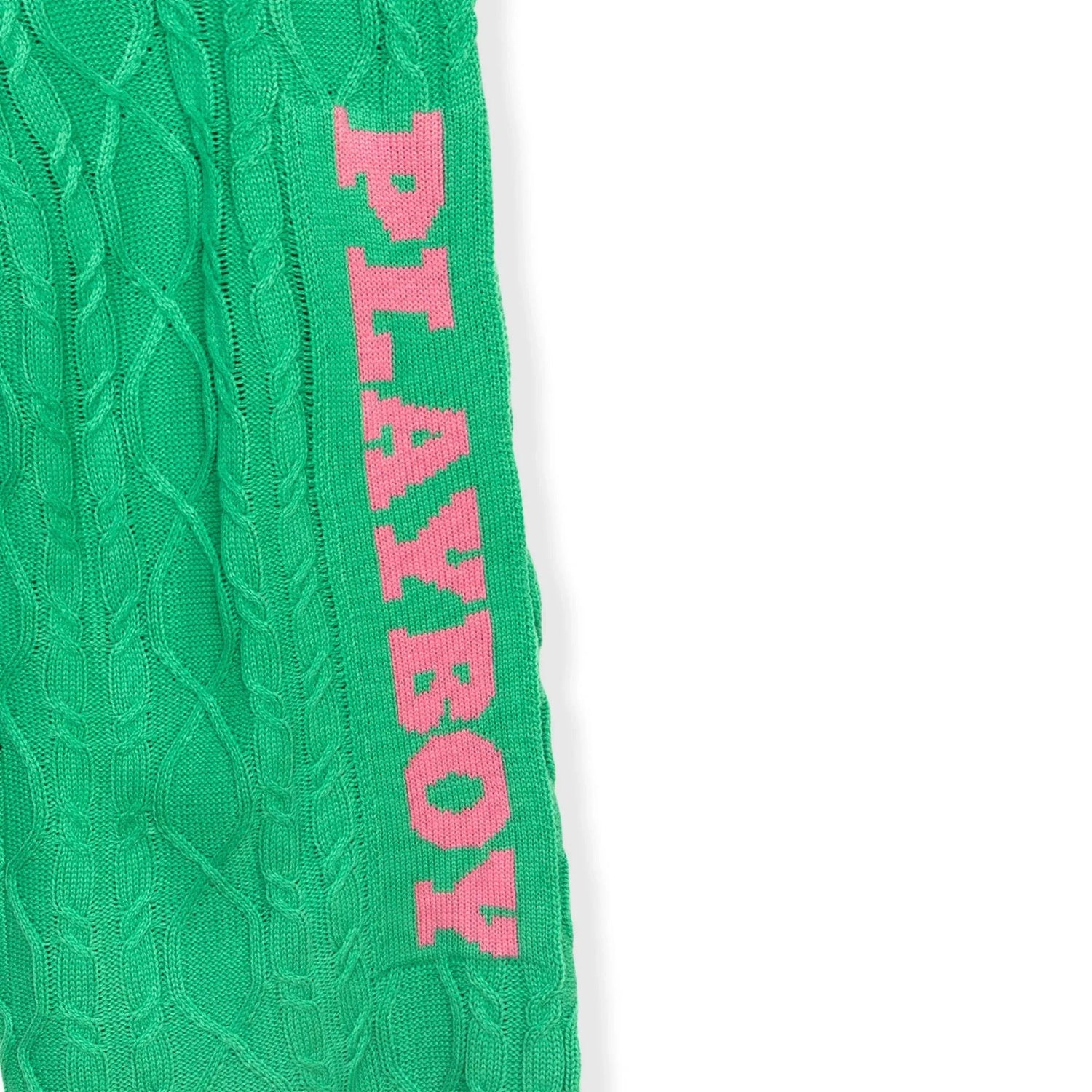 Green cable knit pant leg with pink PLAYBOY text, close-up on textured fabric