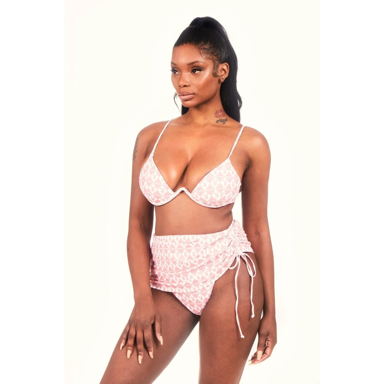 Woman wearing pink monogram mini sarong bikini set with ruched side detail