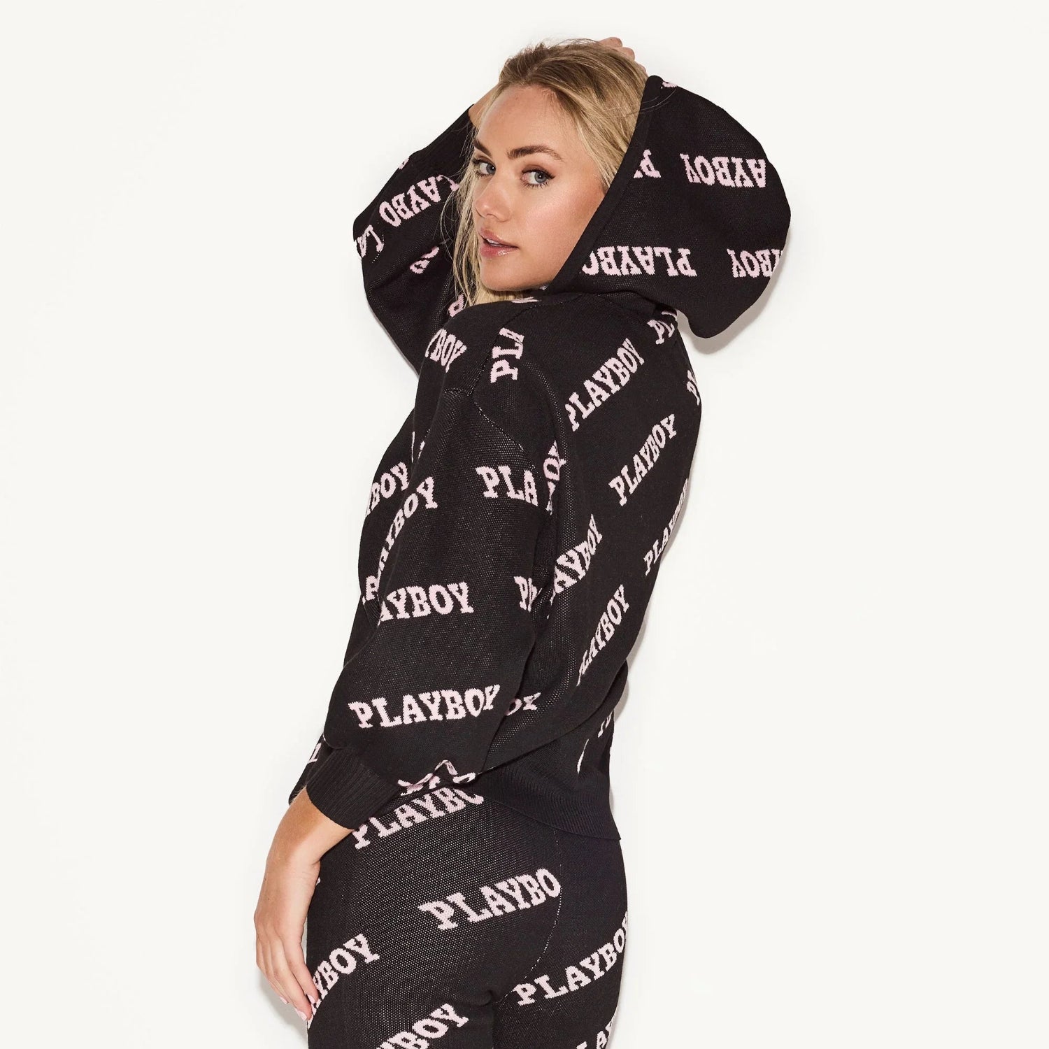 Woman in black intarsia knit leggings and matching hoodie with all-over logo pattern