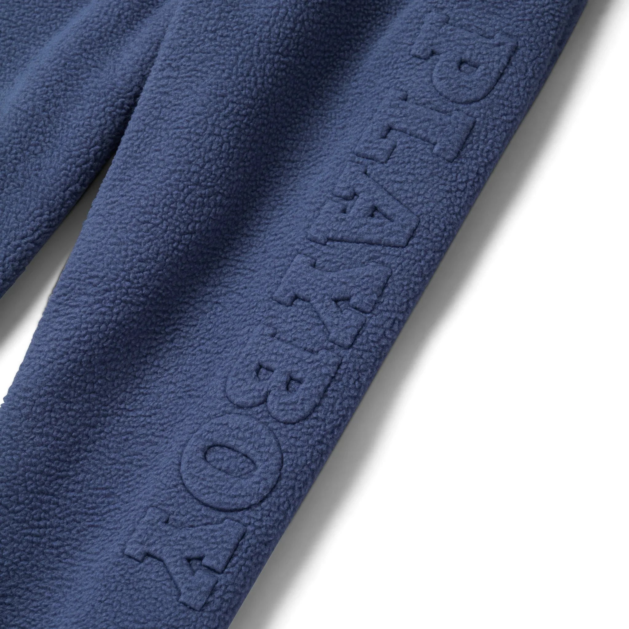 Close-up of blue women's polar fleece sweatpants with textured PLAYBOY lettering on leg