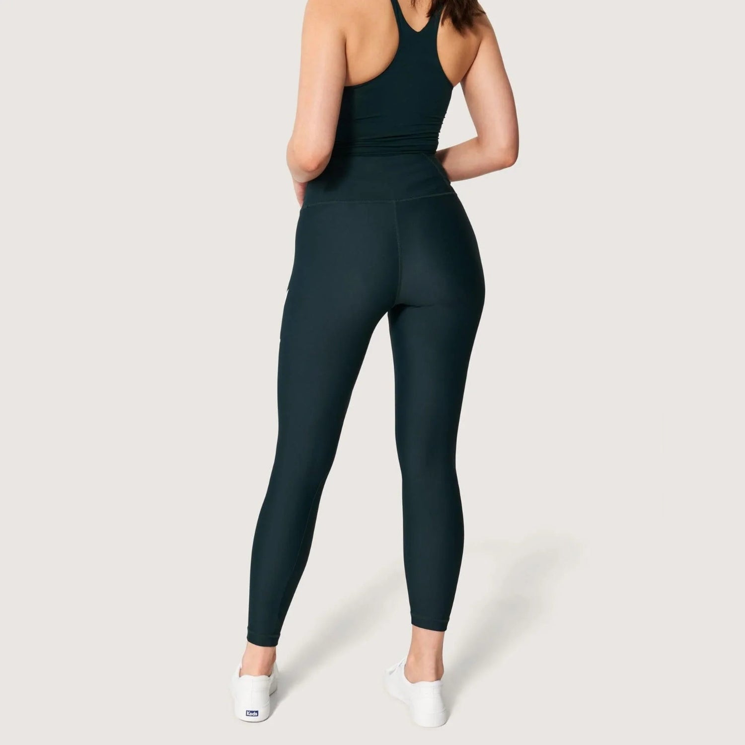 Woman modeling high-waisted black leggings with rabbit head logo, back view, white background