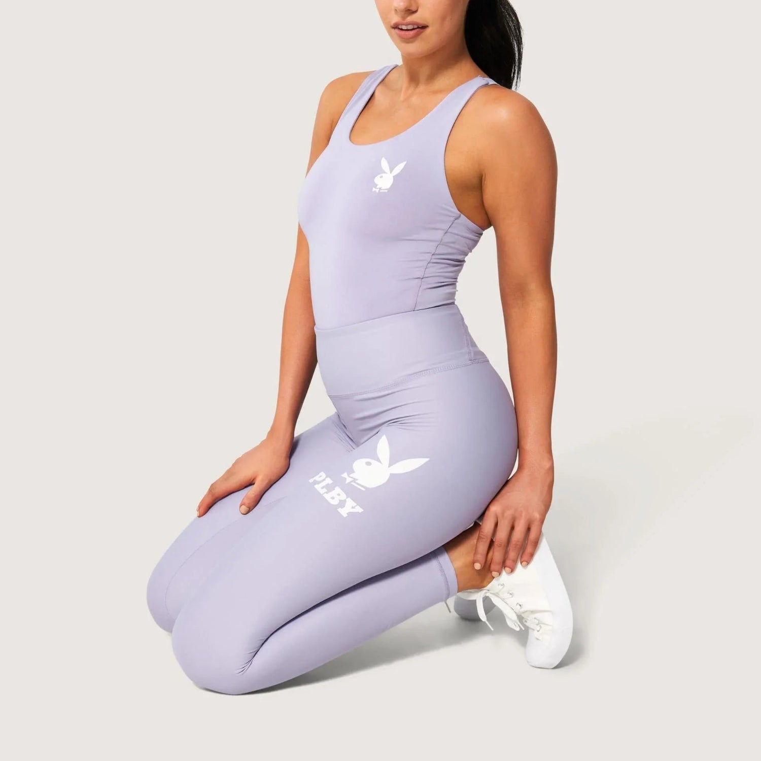 Woman wearing lilac workout set with white rabbit head logo and text on leggings and top