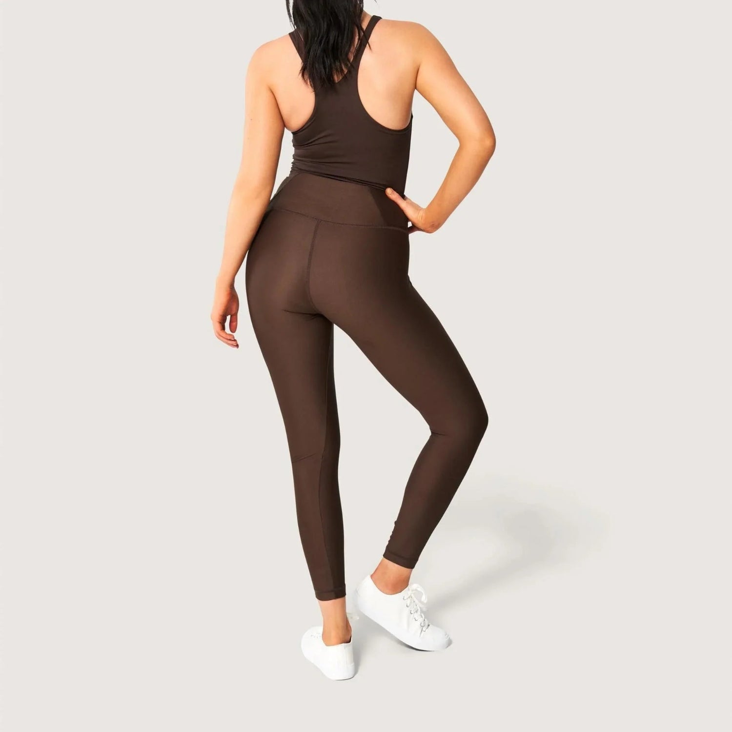 Woman wearing brown high-waisted leggings and matching tank top, back view