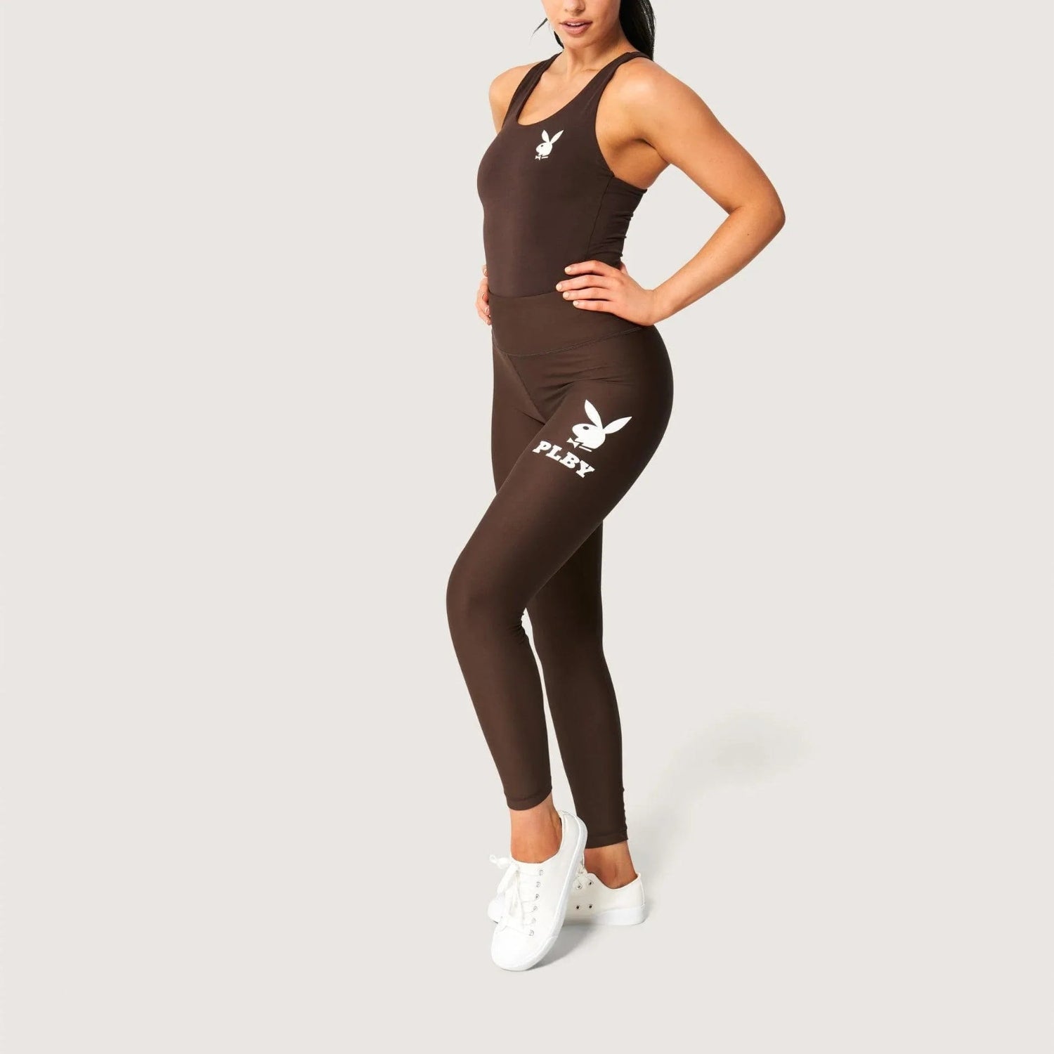 Woman modeling brown active leggings with white bunny head graphic and sporty white sneakers