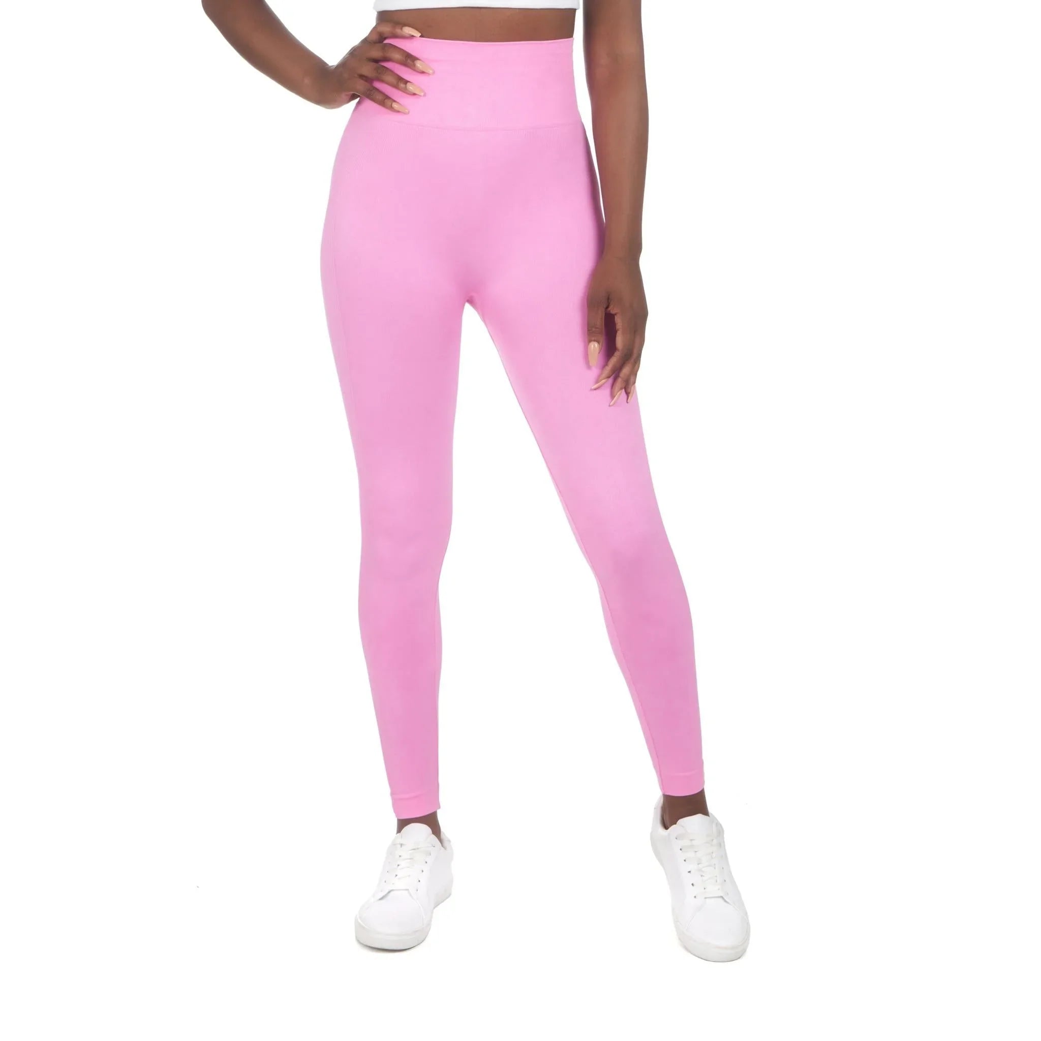 Woman wearing pink high-waisted sport leggings and white sneakers on white background