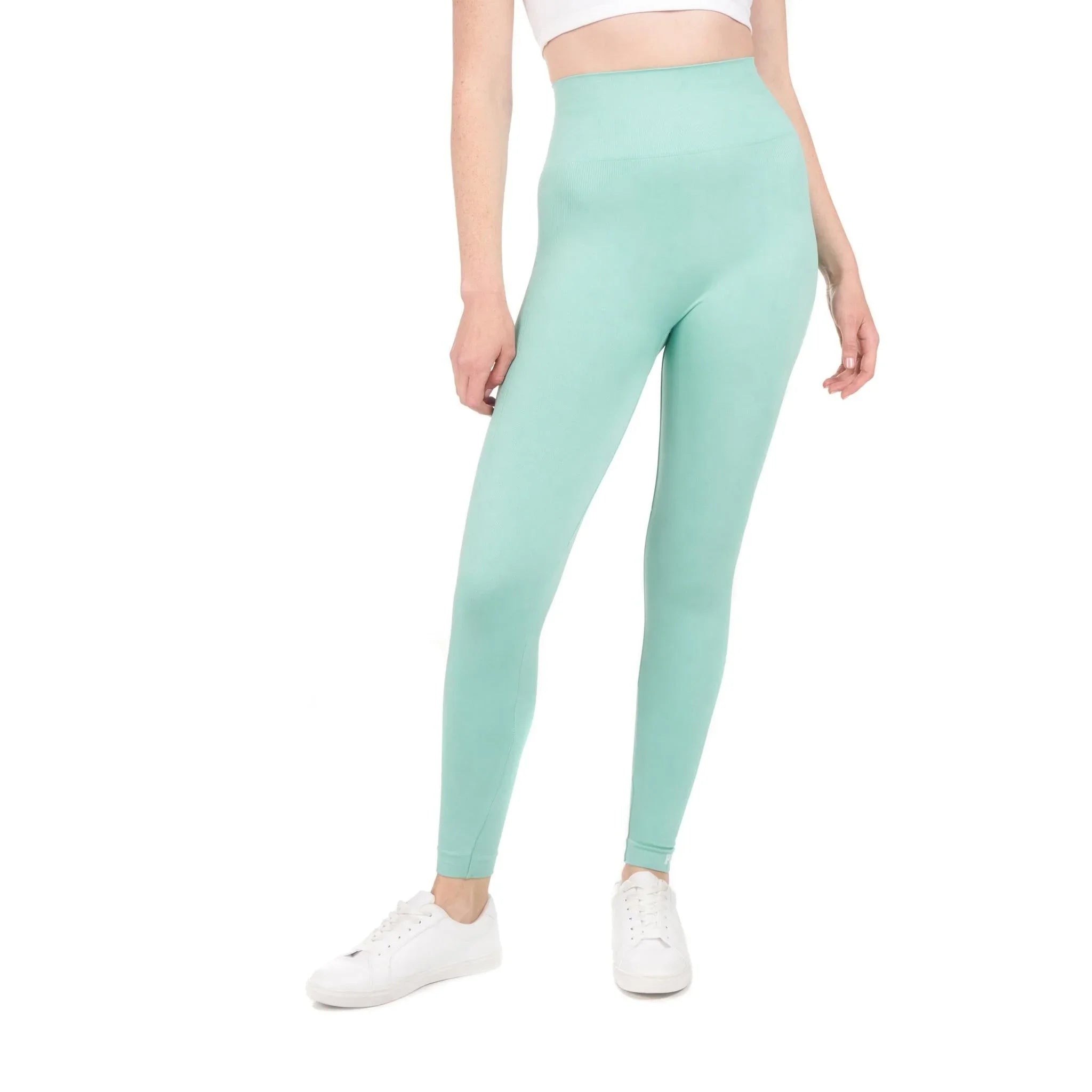 Woman wearing high-waisted mint green sport leggings, cropped white top, and white sneakers