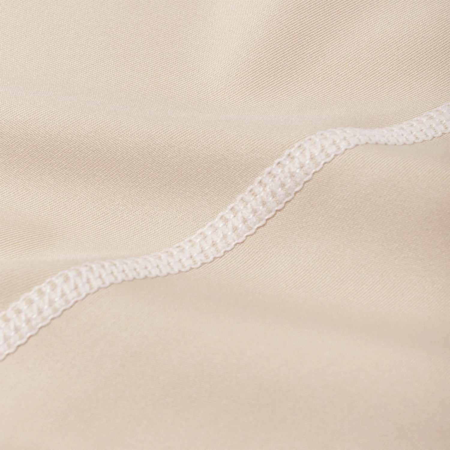 Close-up of beige active leggings fabric with visible ruched waistband stitching detail.