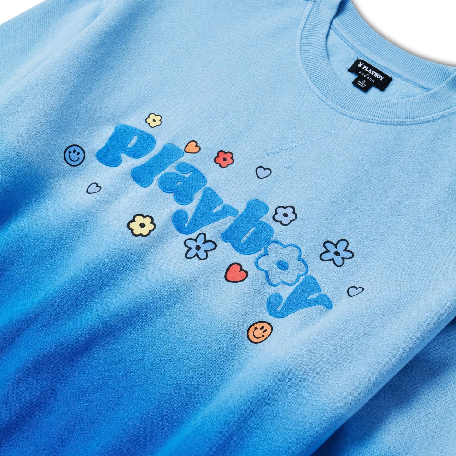 Light blue crew neck sweatshirt with playful flower and heart graphics and large text on front.