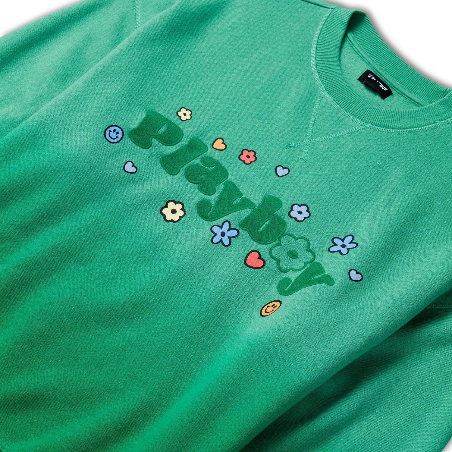 Green crew neck sweatshirt with playful floral, heart, and smiley face graphics and bold text