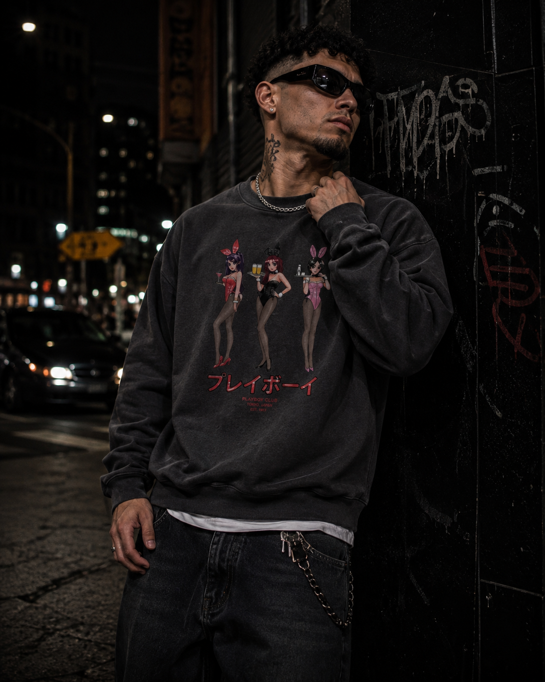 A man wearing a dark gray graphic sweatshirt with a 'Playboy' bunny logo and red Japanese text, posing on a dark urban street at night. #Streetwearmen