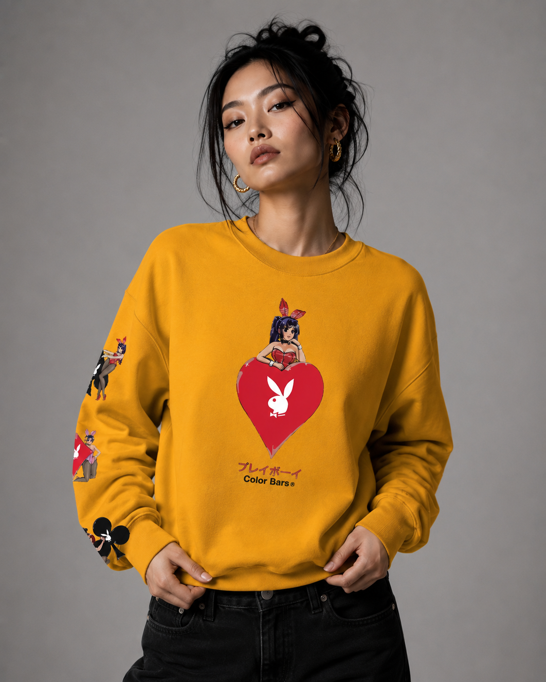 A woman modeling a mustard yellow crewneck sweatshirt featuring a red heart graphic with the white Playboy bunny logo and 'Don't Be A Bunny' text, paired with black jeans against a neutral gray studio background.