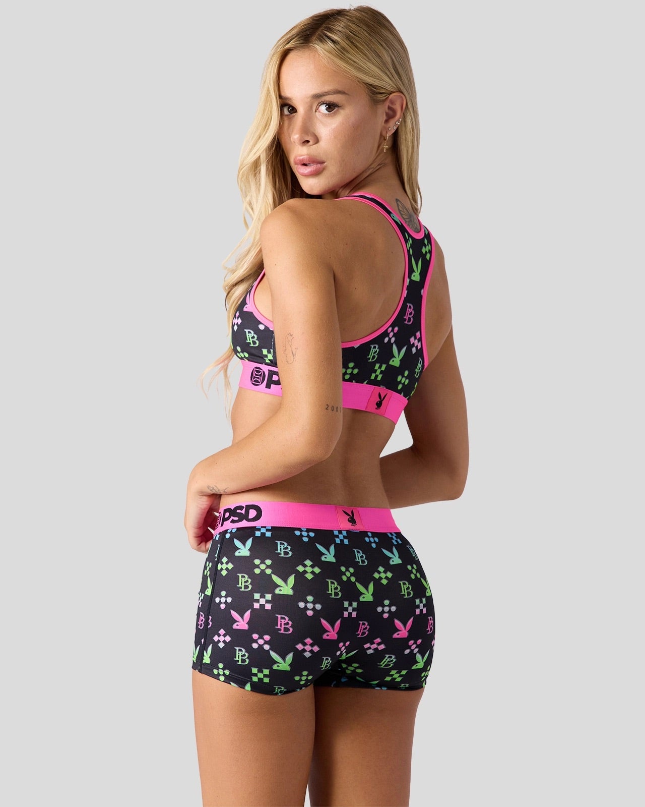 Woman wearing a colorful sports bra and shorts set on a plain background
