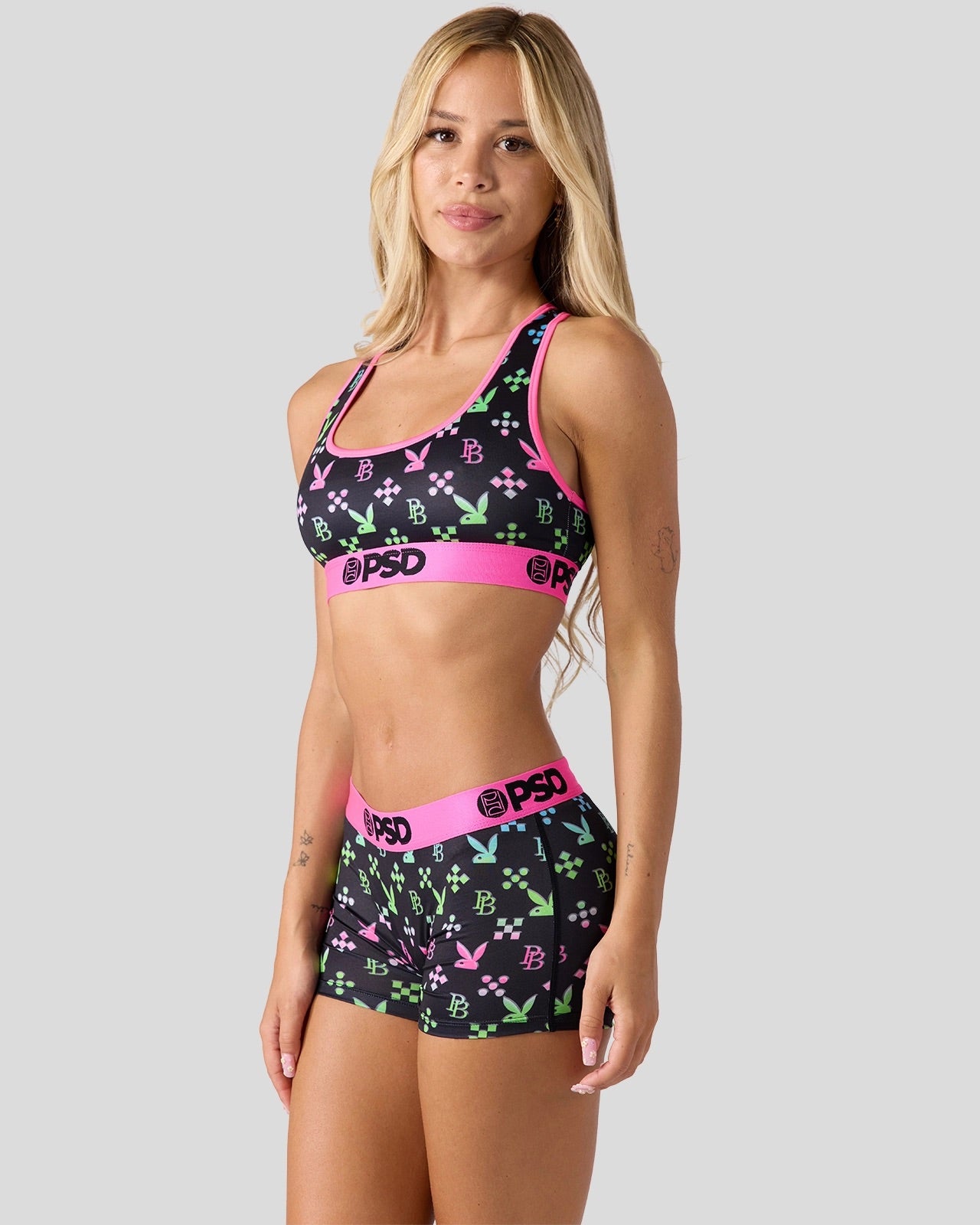 Woman wearing a sports bra and shorts with 'PSD' branding on a plain background