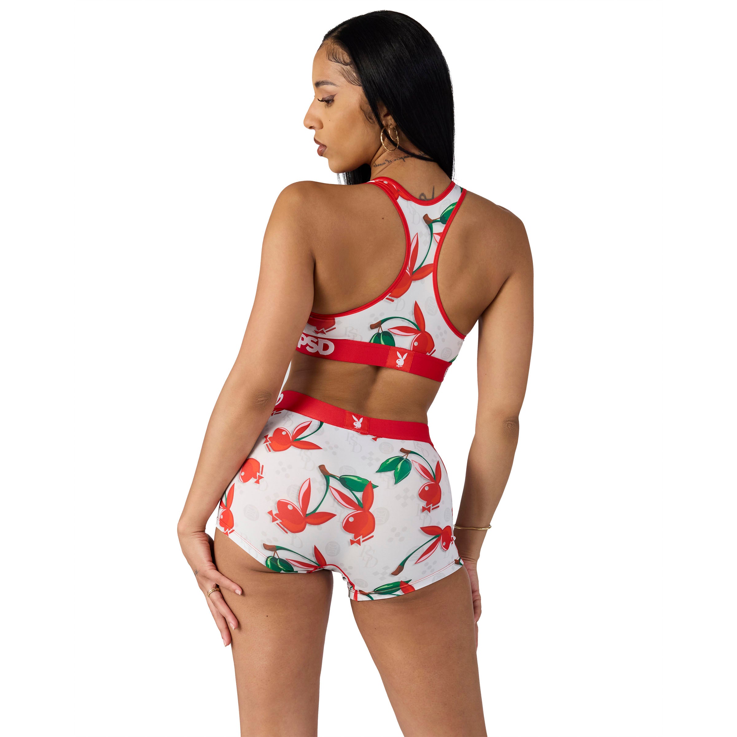 Woman modeling white Playboy sports bra and shorts set with red and green cherry print