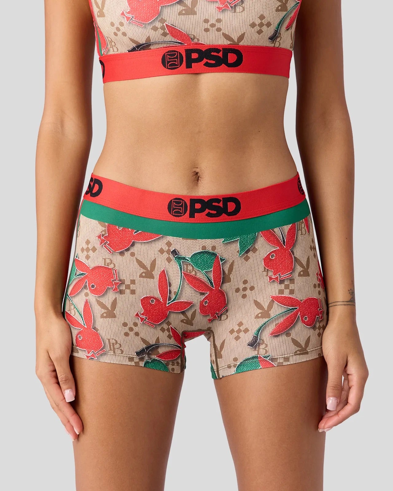 A model wearing a matching two-piece lingerie set with a beige and red bunny pattern, featuring a red waistband with 'PSD' in black text and a green waistband.