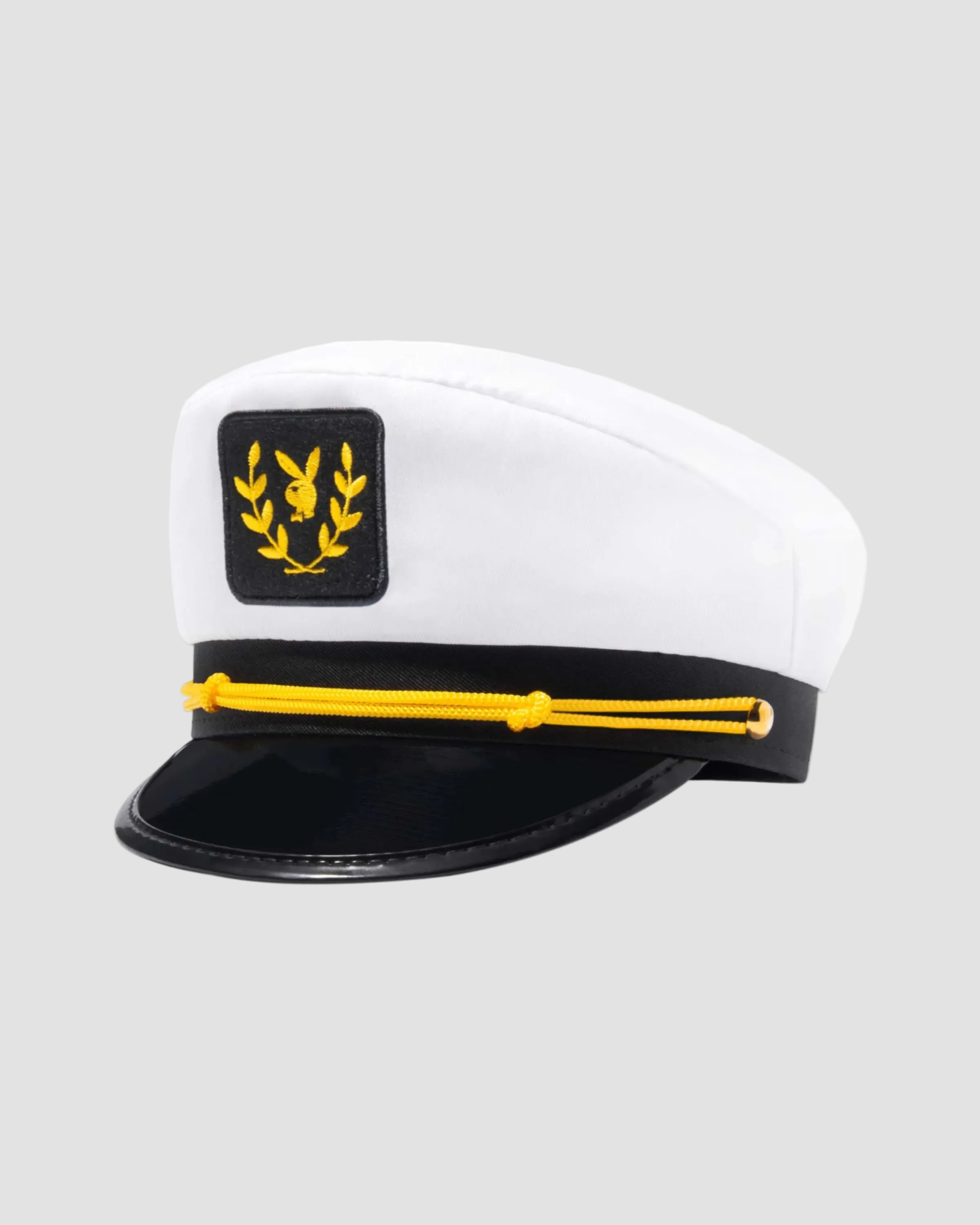A white and black captain-style hat with a black visor, a black band featuring a yellow laurel wreath and central emblem, and a yellow rope detail across the front.
