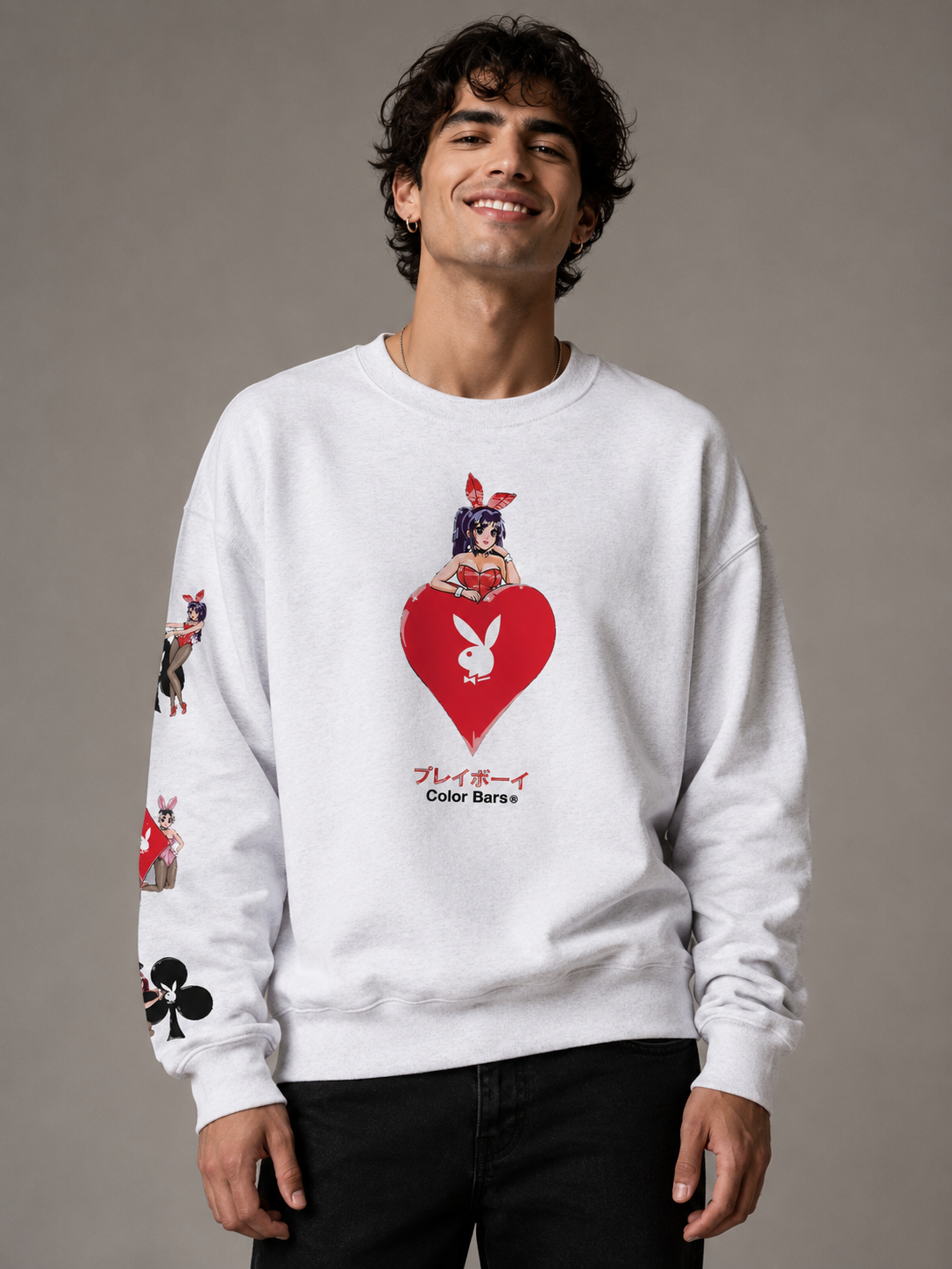 A man wearing a white crewneck sweatshirt featuring a red heart and Playboy bunny graphic on the front, with additional graphics on the sleeves, against a neutral gray studio background.