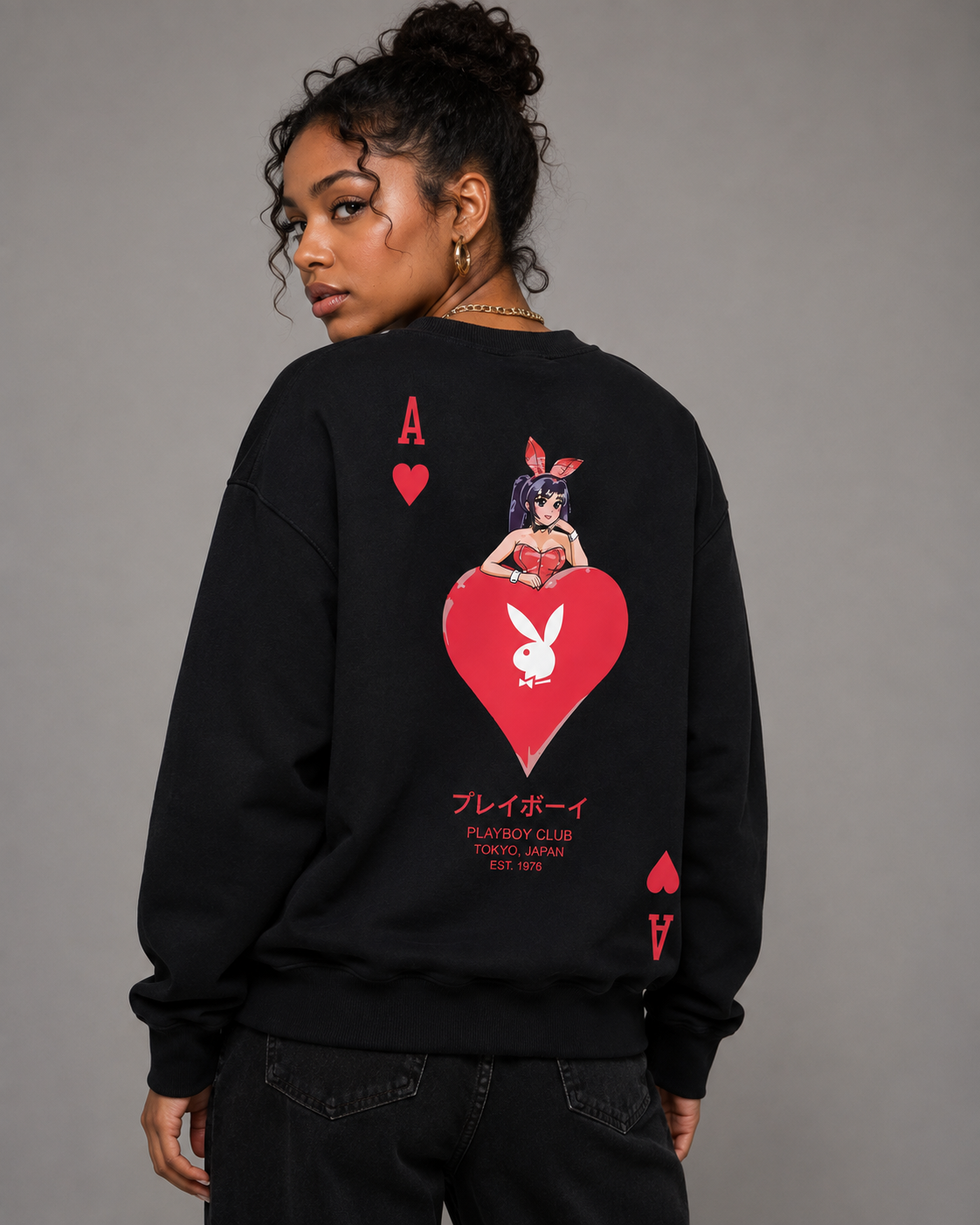 A model wearing a black sweatshirt from the back, featuring a large red and white graphic of an Ace of Hearts playing card with the Playboy bunny logo and Japanese text.