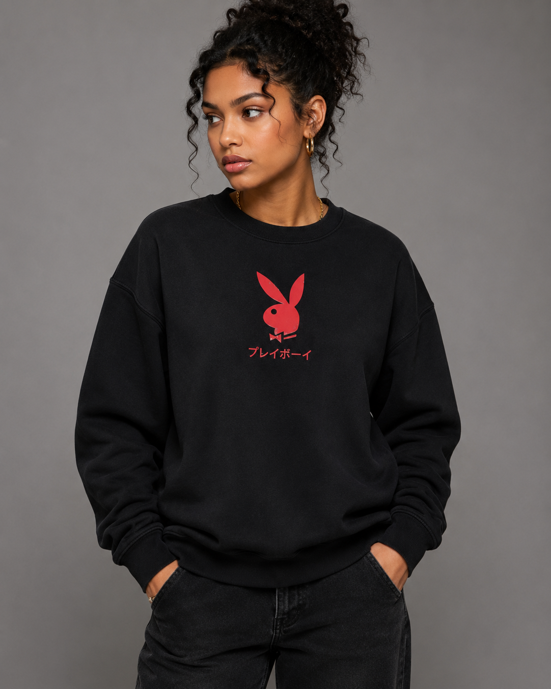 A woman wearing a black crewneck sweatshirt with a red Playboy bunny logo and Japanese text on the chest, paired with black jeans, against a solid gray studio background. #Streetwearwomen