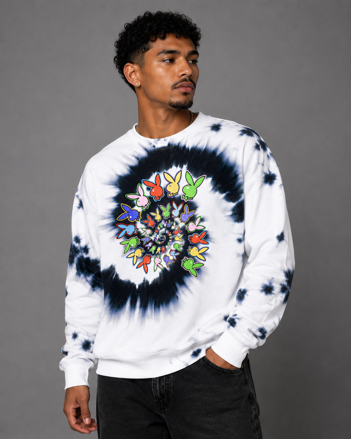 A man wearing a white crewneck sweatshirt with a black tie-dye circular pattern and a colorful butterfly graphic in the center, paired with black jeans, against a solid gray studio background.