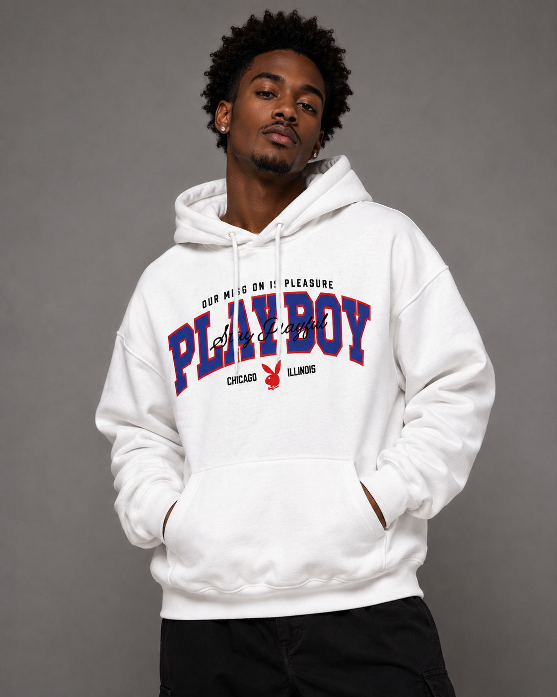A man wearing a white oversized hoodie with a red and blue 'PLAYBOY' graphic on the front, posed against a solid gray studio background.