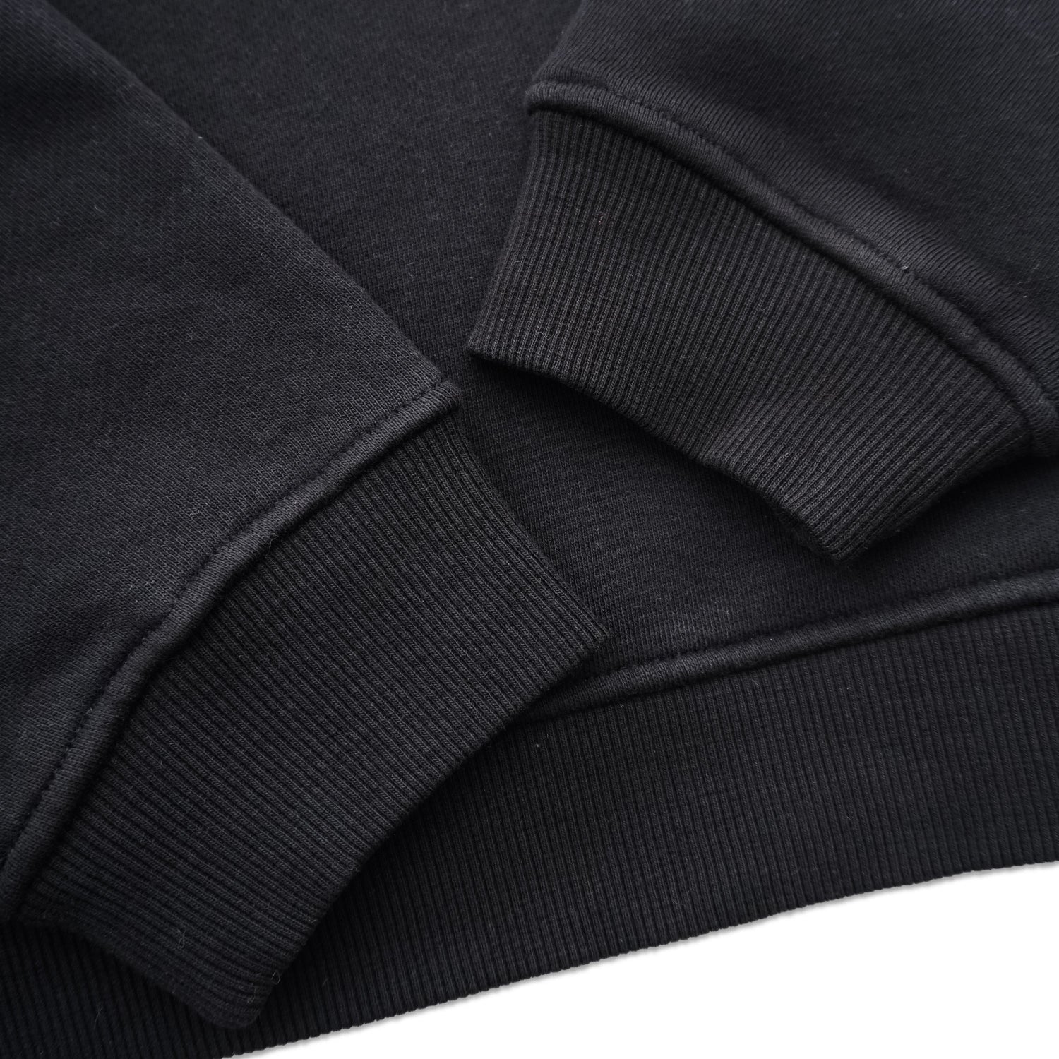 Close-up of black crewneck sweatshirt cuffs and hem with ribbed knit texture