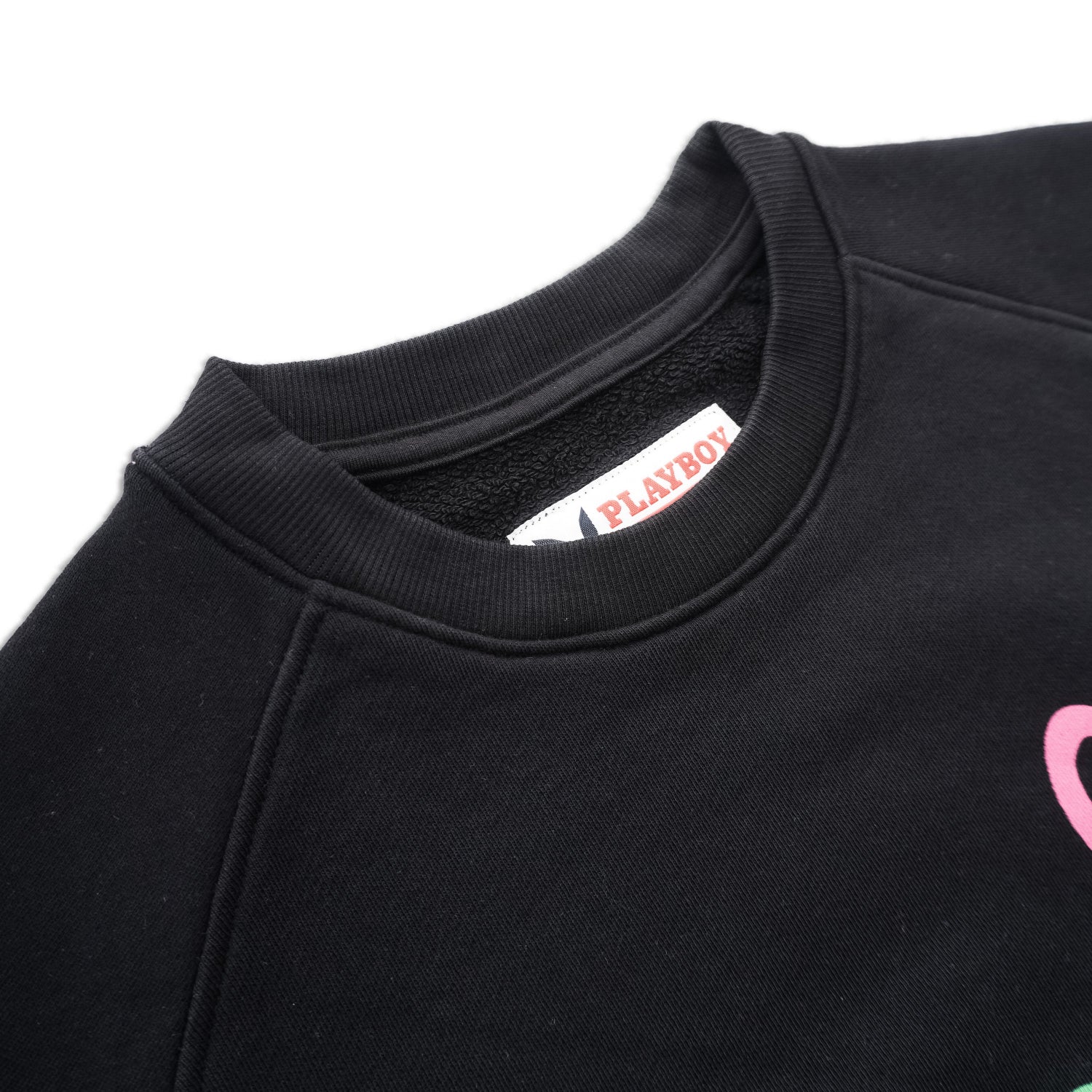 Close-up of black crewneck sweatshirt with pink graphic and visible tag on collar