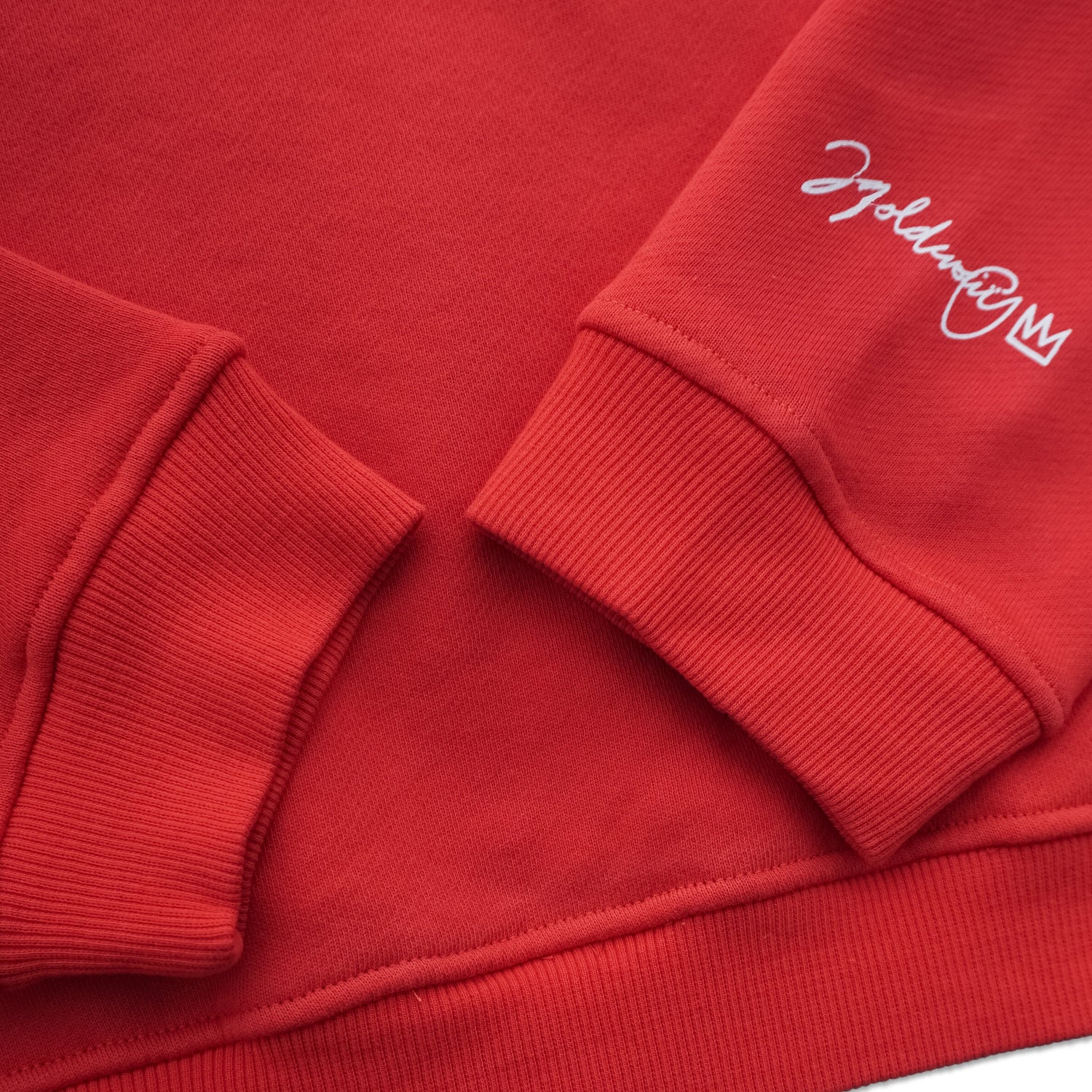 Close-up of red crewneck sweatshirt sleeves with white script on cuff