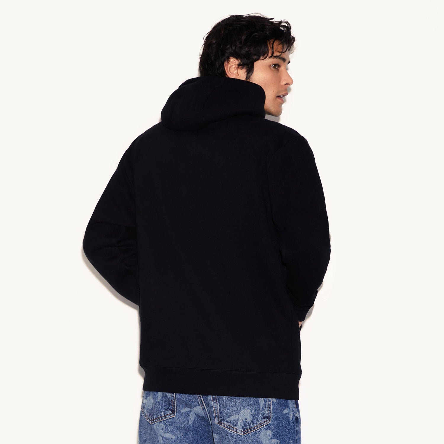 Person wearing a black hoodie from the back on a white background