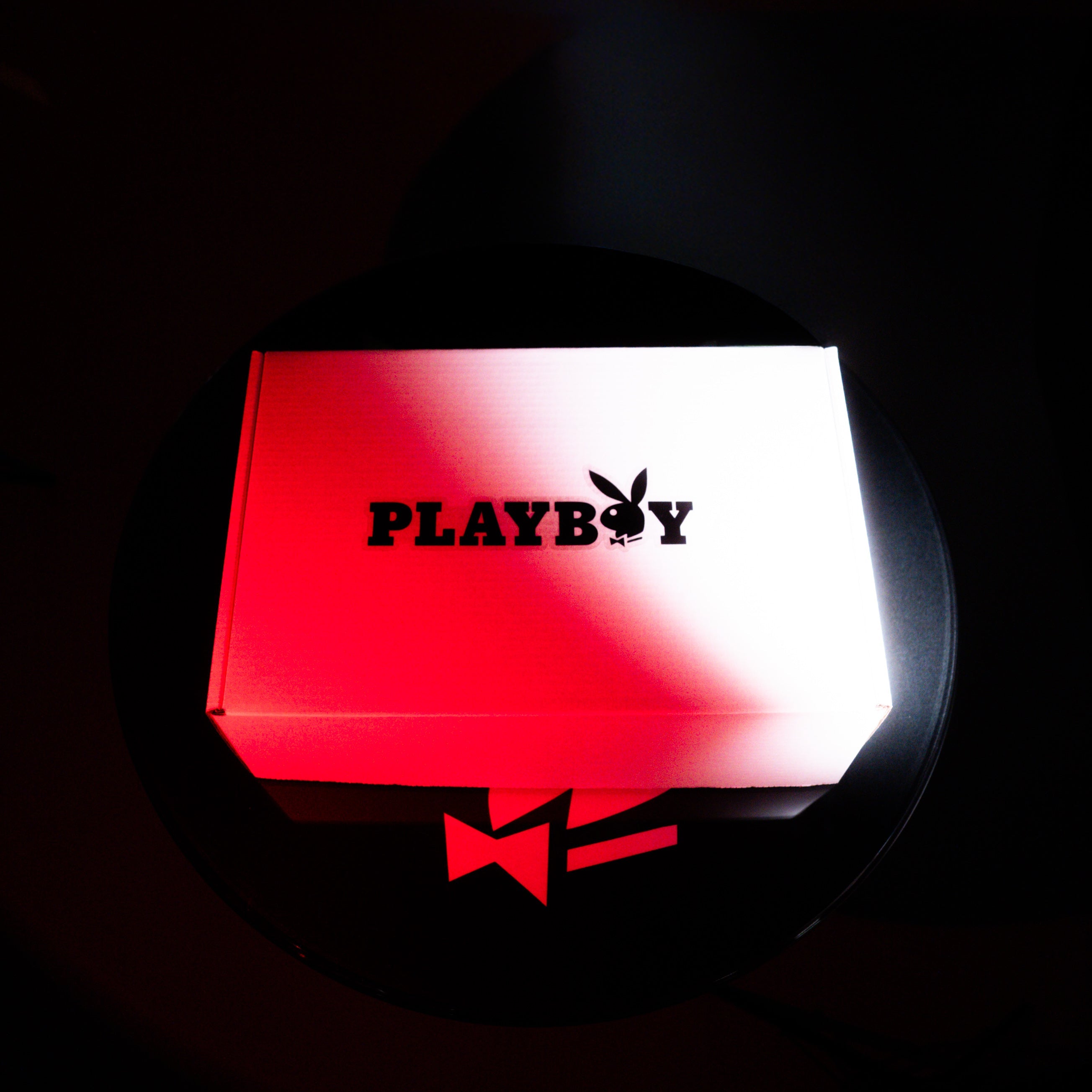 Playboy product packaging with red and white gradient on a dark background