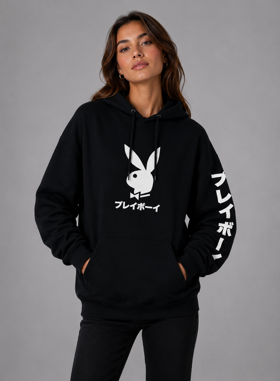 A woman modeling a black pullover hoodie with a white Playboy bunny logo and Japanese text on the front, plus white Japanese text down one sleeve, against a plain gray studio background. #Women