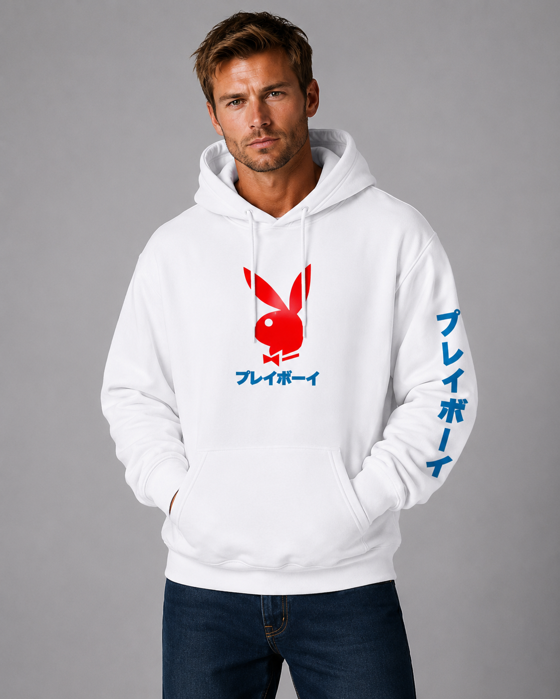 A man wearing a white pullover hoodie with a red Playboy bunny logo and blue Japanese text on the front and sleeve, paired with dark blue jeans, against a solid gray studio background.
