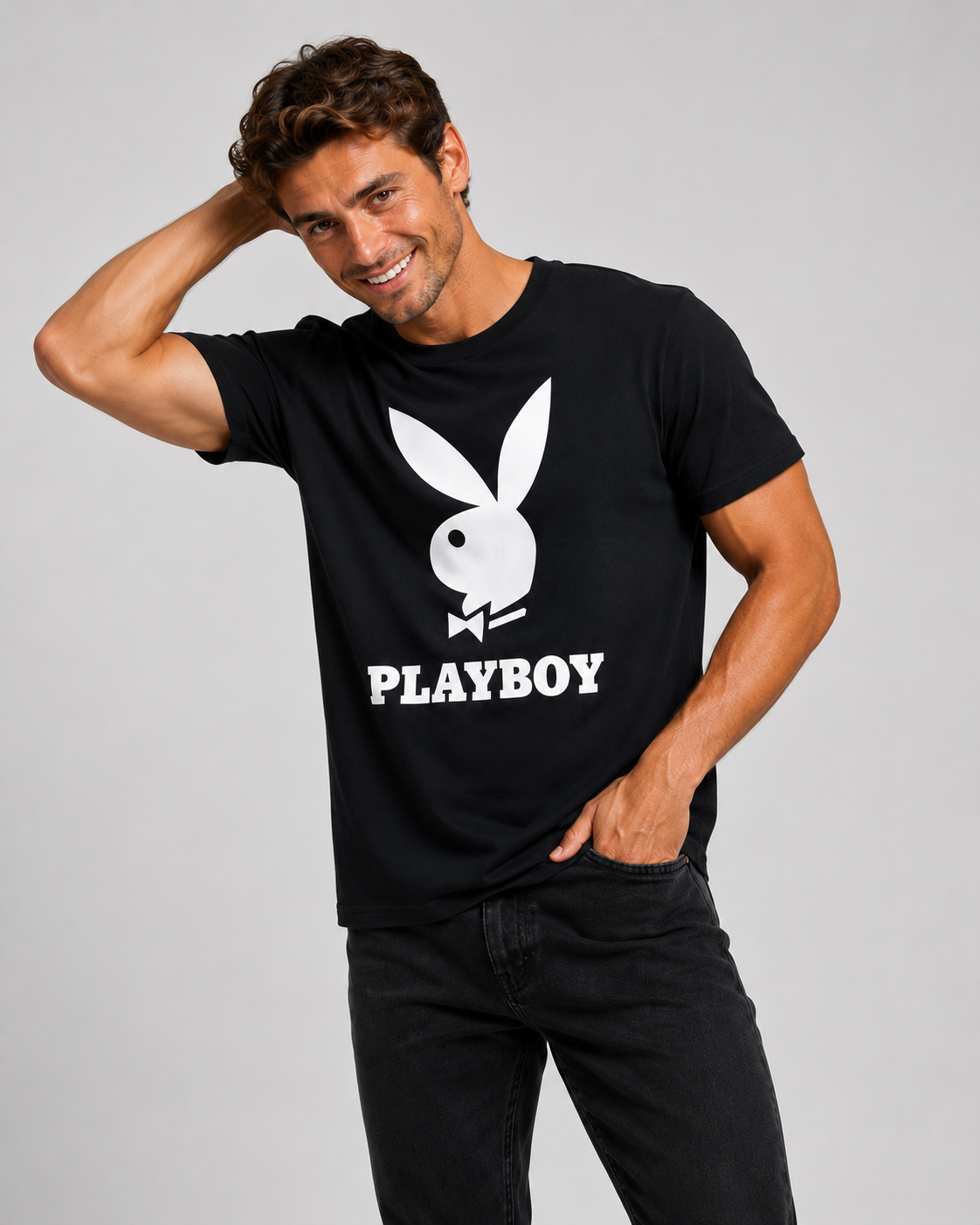 A man wearing a black short-sleeve t-shirt with a large white Playboy bunny logo and the word 'PLAYBOY' printed on the front, posed against a solid gray studio background.