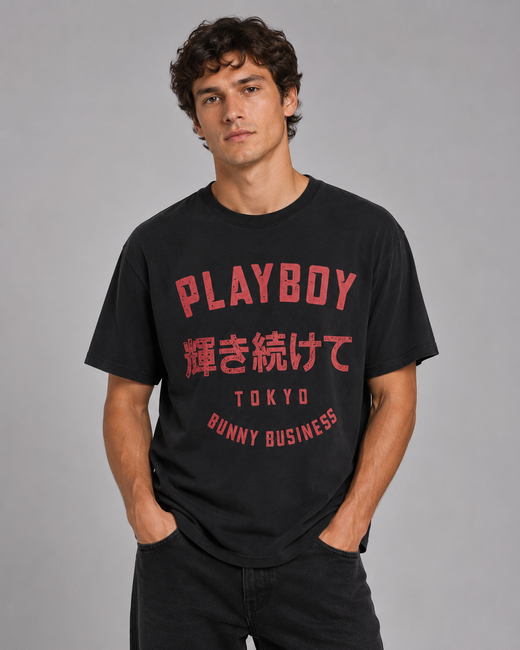 A man wearing a black short-sleeve t-shirt with red graphic text on the front, including 'PLAYBOY' and Japanese characters, posed against a solid gray studio background.