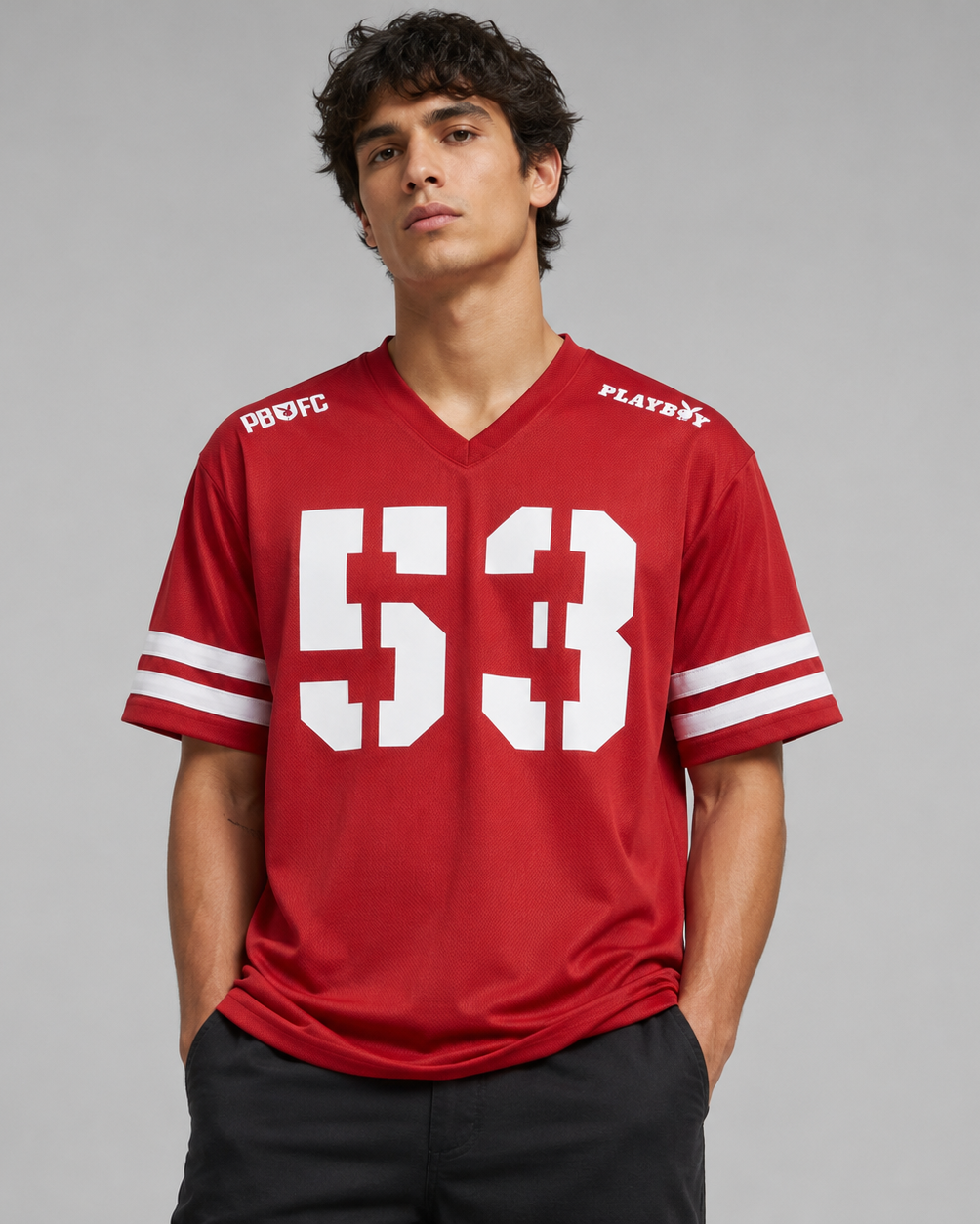 A man wearing a red V-neck athletic jersey with large white '53' on the front, white sleeve stripes, and 'PROFC' and 'PLAYBYE' text on the shoulders, photographed against a light gray studio background.