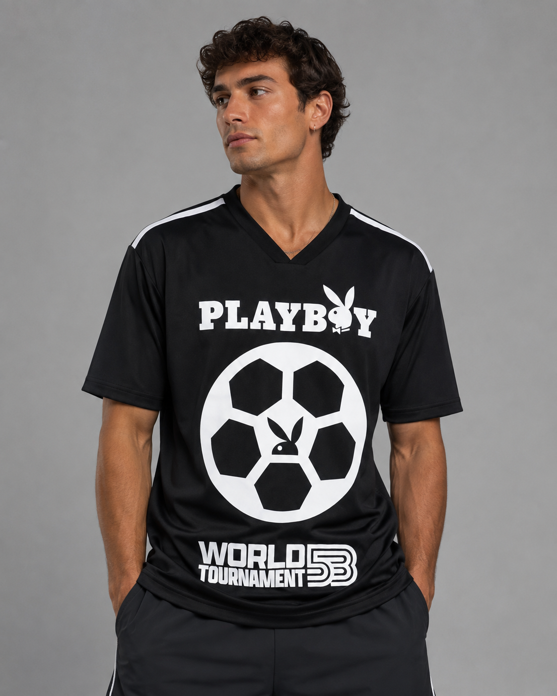 A man wearing a black short-sleeve V-neck t-shirt with white graphics. The shirt features the Playboy bunny logo and 'PLAYBOY' text on the chest, a large soccer ball graphic, and 'WORLD TOURNAMENT 5B' printed near the hem.