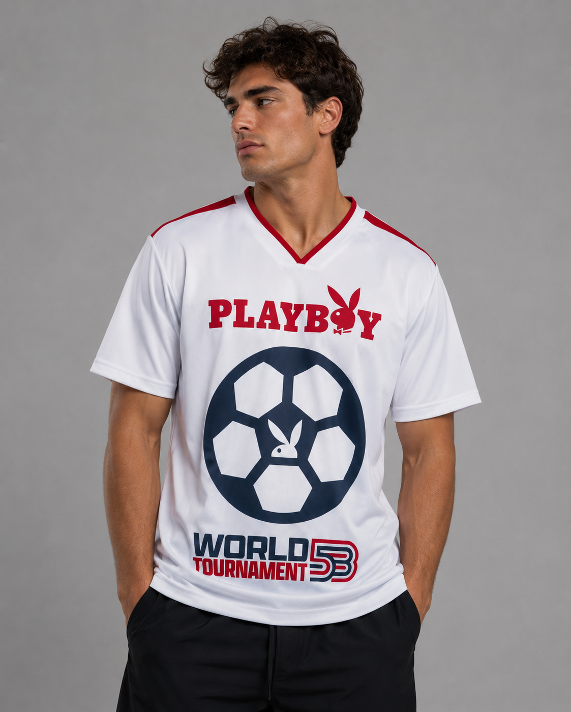 A man wearing a white short-sleeve V-neck t-shirt with red and navy graphics. The shirt features the red 'PLAYBOY' logo with the bunny head on the chest, a large navy soccer ball graphic with a bunny head in the center, and 'WORLD TOURNAMENT 53' printed below.