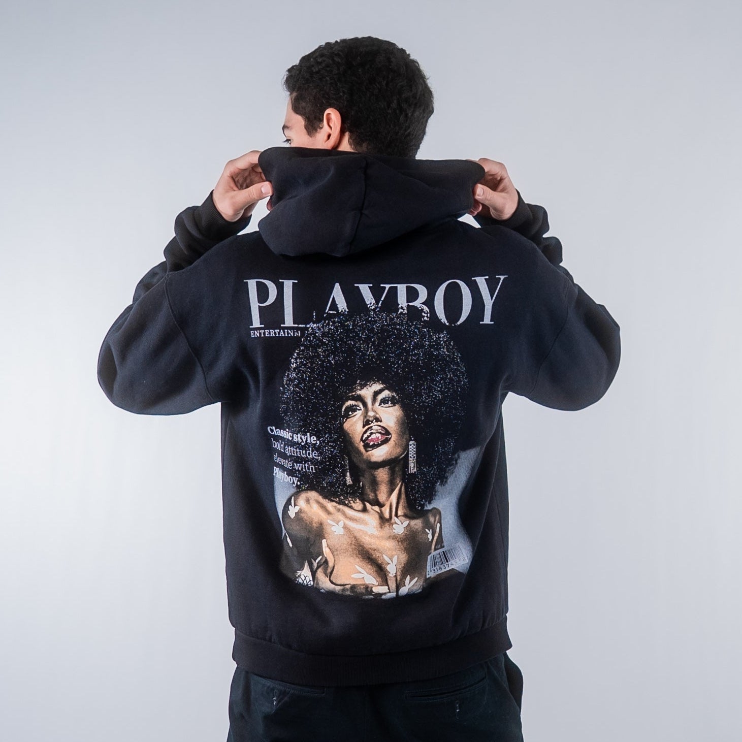 Model wearing black Playboy hoodie with graphic cover print and bold logo on back
