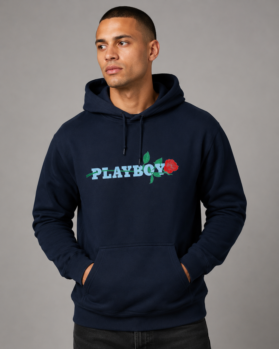 A man wearing a navy blue pullover hoodie with a colorful 'PLAYBOY' rose logo on the chest, posed against a solid gray studio background.