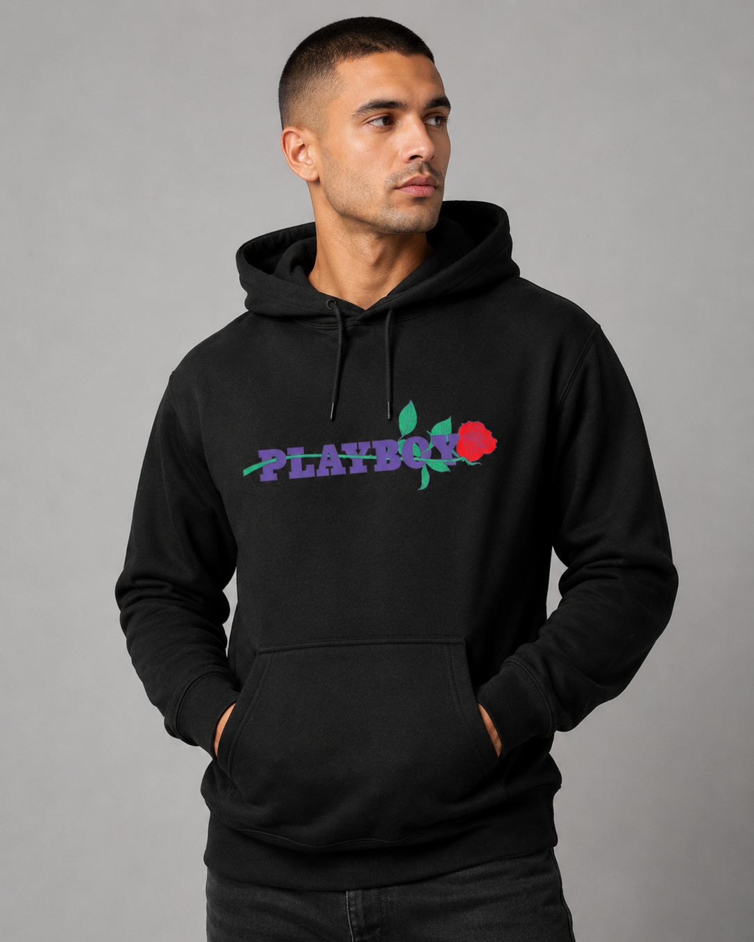 A man wearing a black pullover hoodie with a colorful 'PLAYBOY' rose graphic on the chest, posed against a solid gray studio background.