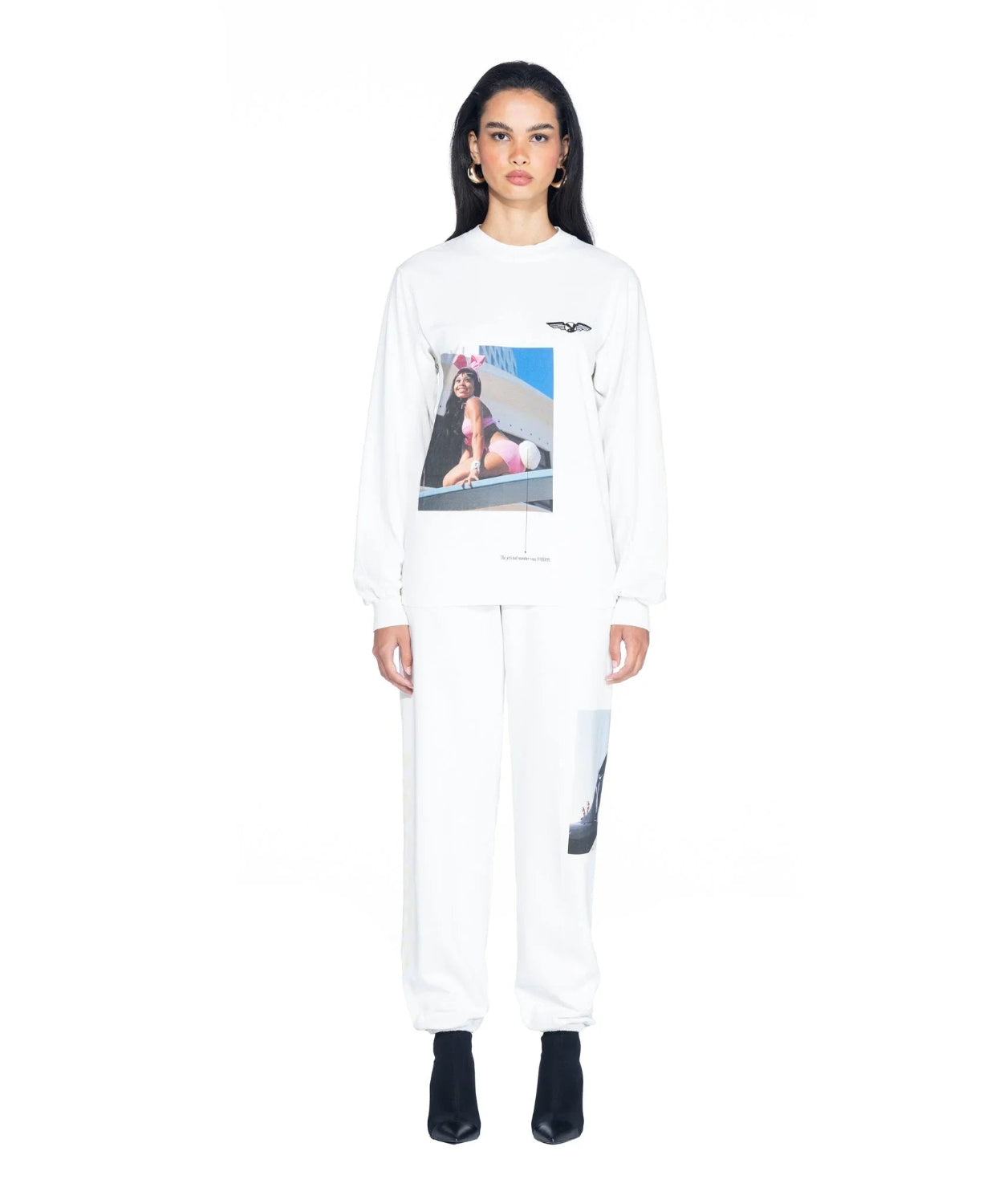 Woman wearing white long sleeve T-shirt with aviation-themed graphic and matching white pants.