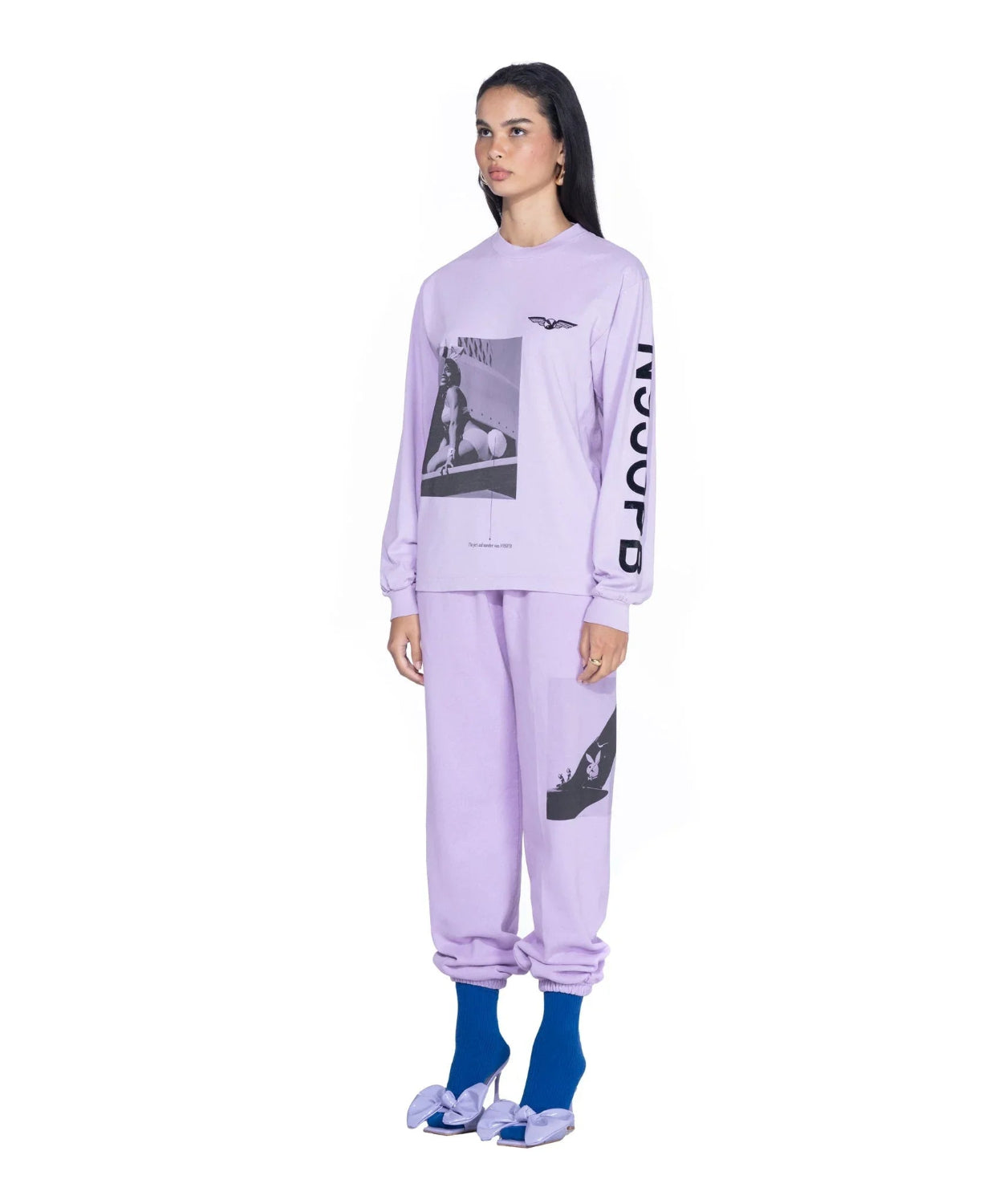 Woman wearing lavender aviation-themed long sleeve shirt and matching sweatpants with graphic prints.
