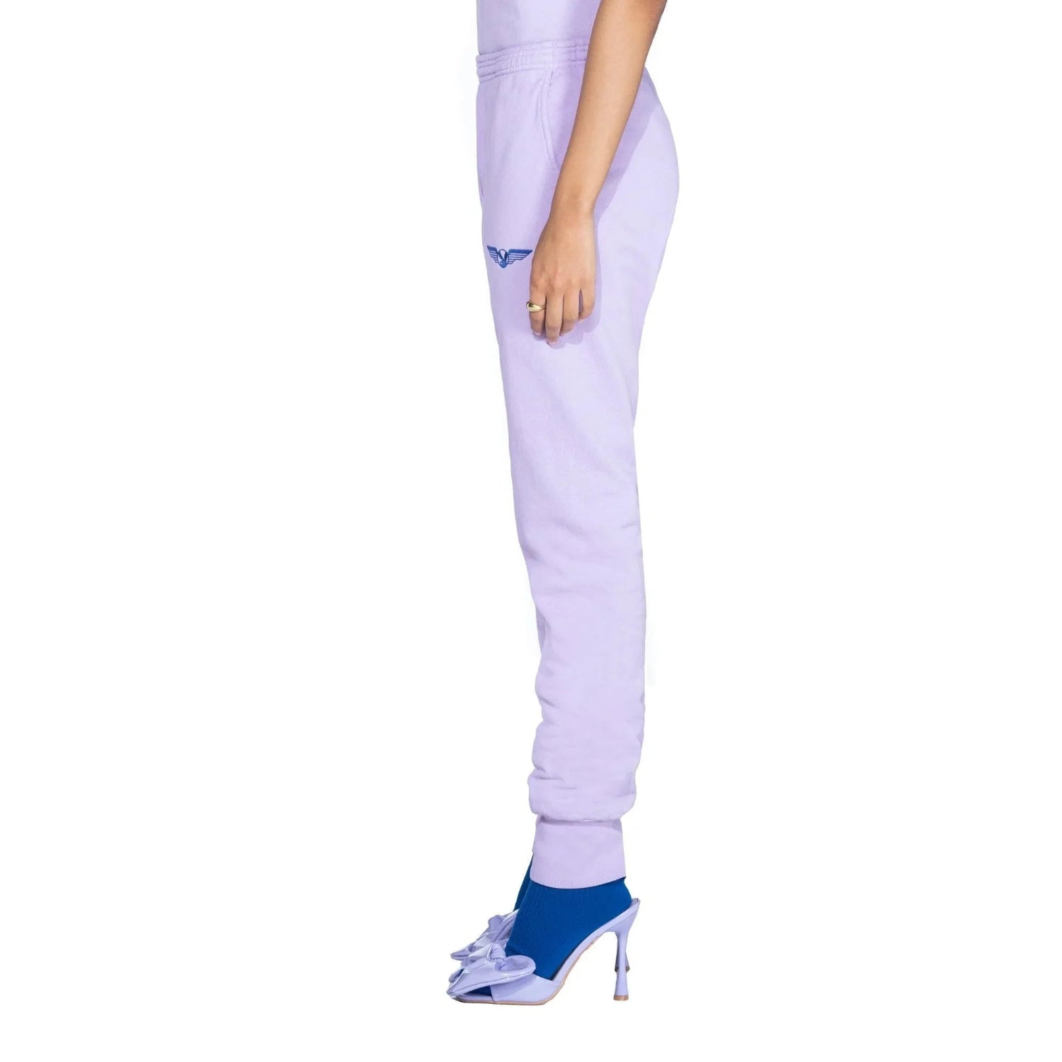 Side view of lavender sweatpants with blue wing graphic, styled with blue heels