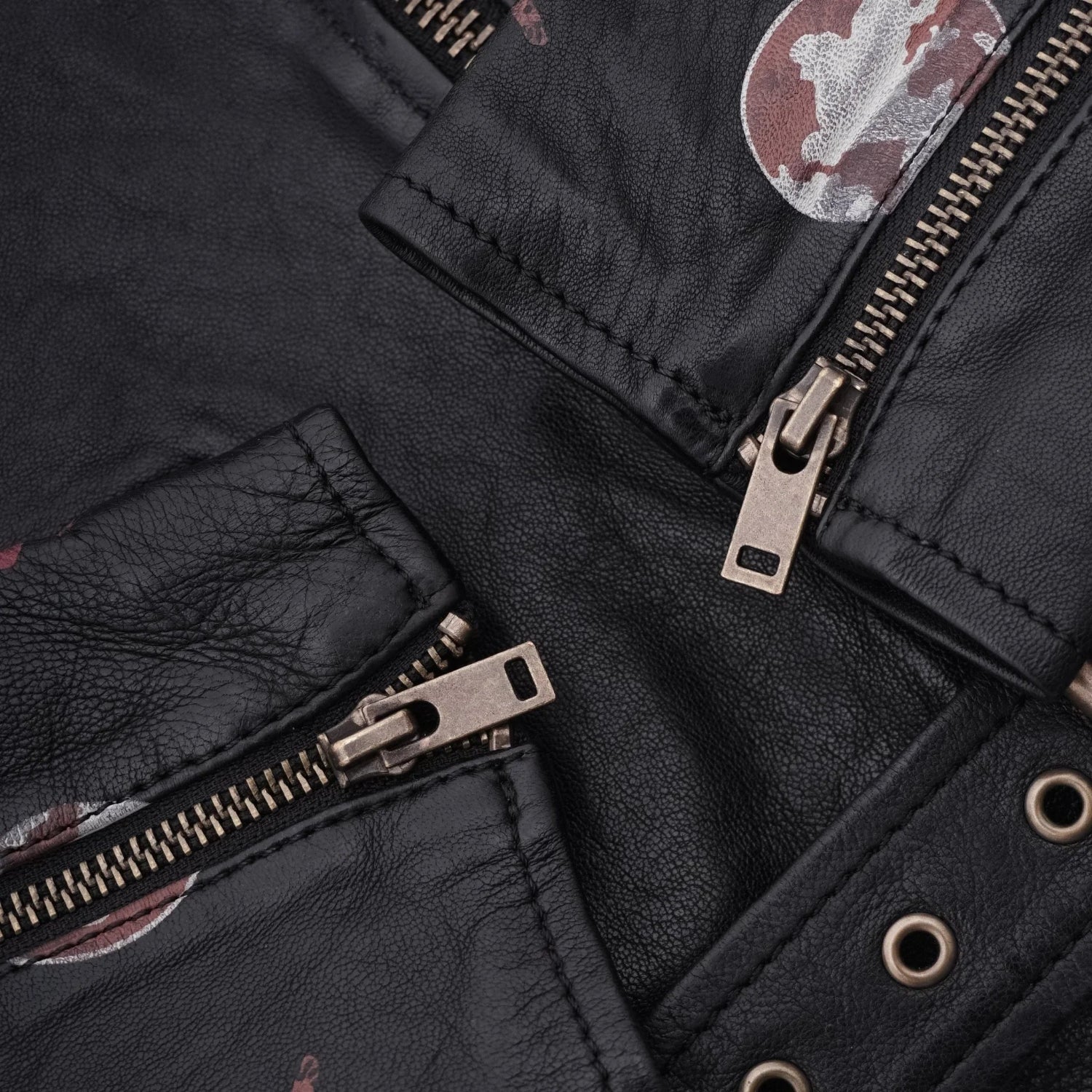 Close-up of black women's leather jacket with metal zippers and grommet details