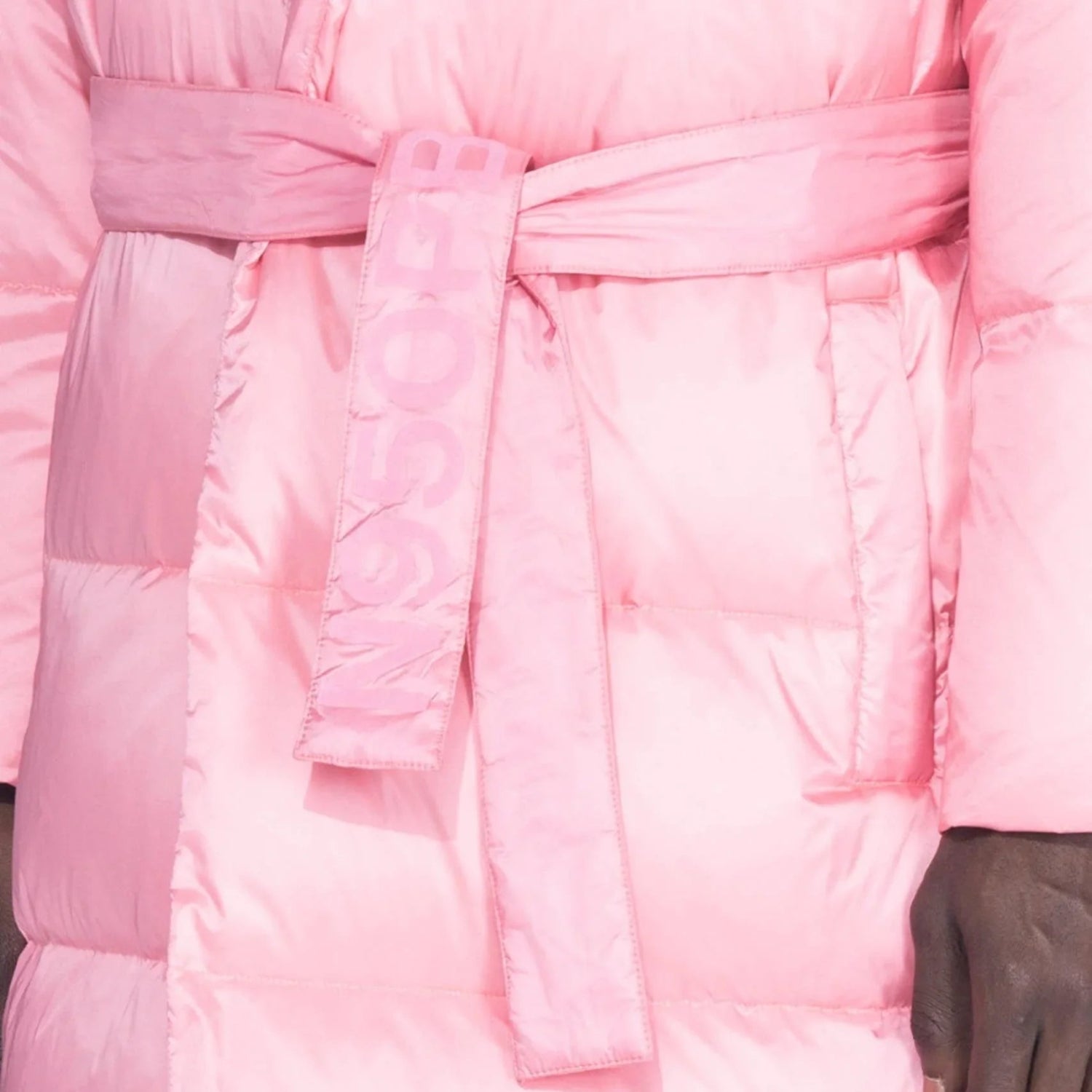 Close-up of pink belted long puffer jacket with waist tie and quilted details