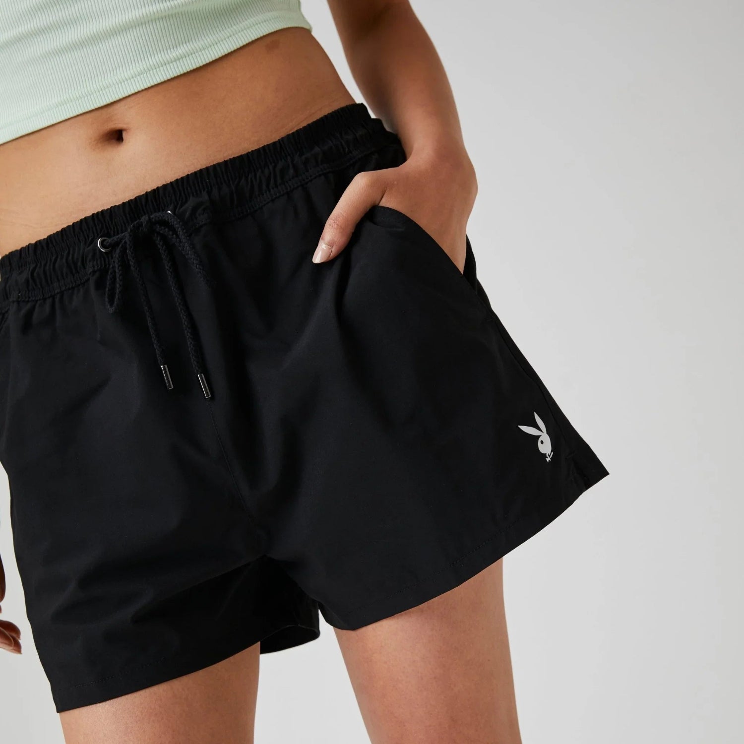 Woman wearing black board shorts with bunny logo and elastic drawstring waistband